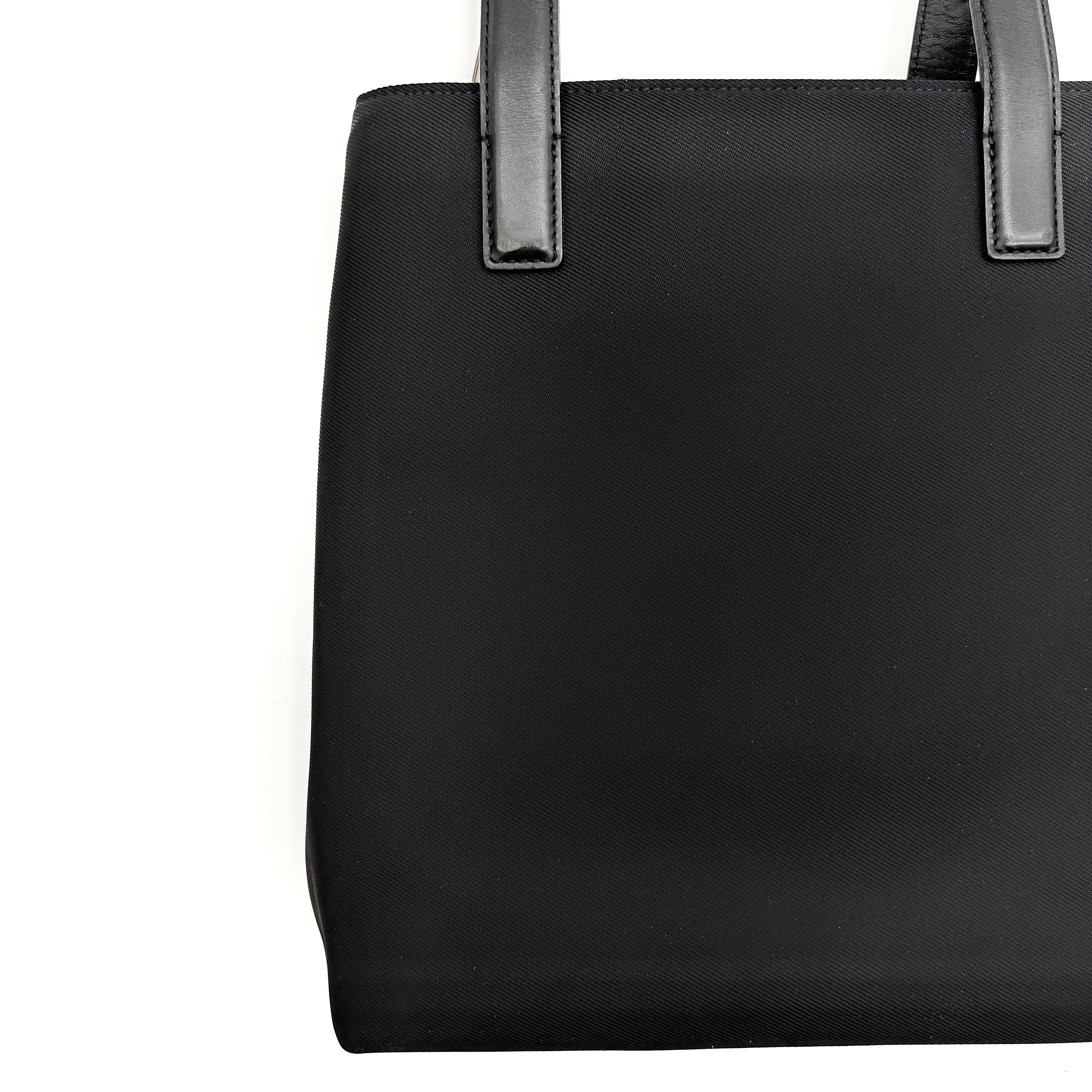 Coach Mercer Nylon Tote Bag in black with leather handles and silver Coach tag, photographed on a white background.