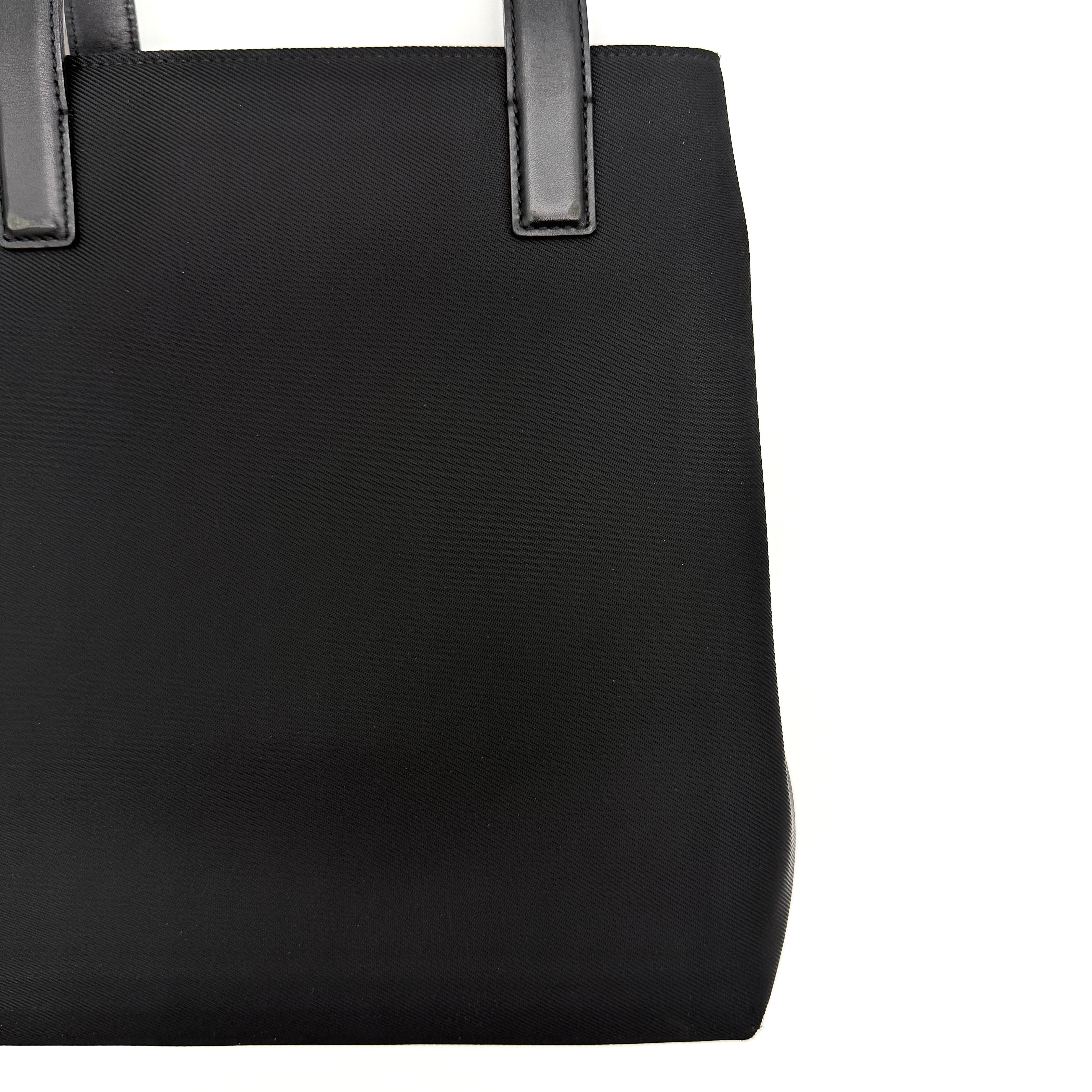 Coach Mercer Nylon Tote Bag in black with leather handles and silver Coach tag, photographed on a white background.