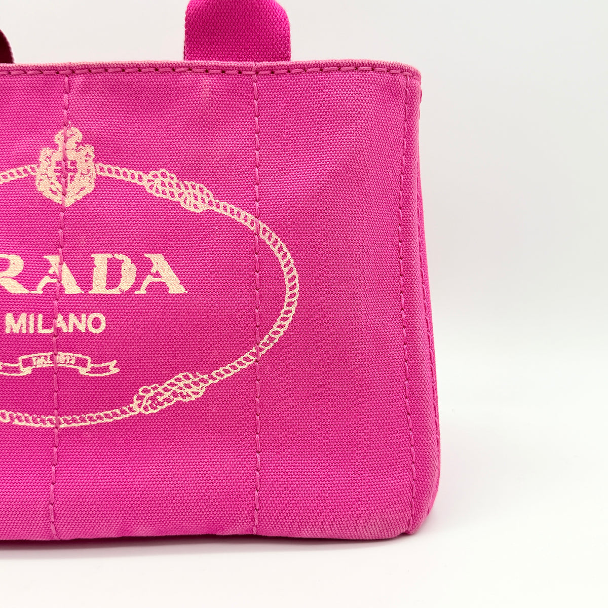 Light pink Prada Canapa tote bag in canvas with gold-tone hardware, shown on a white background.