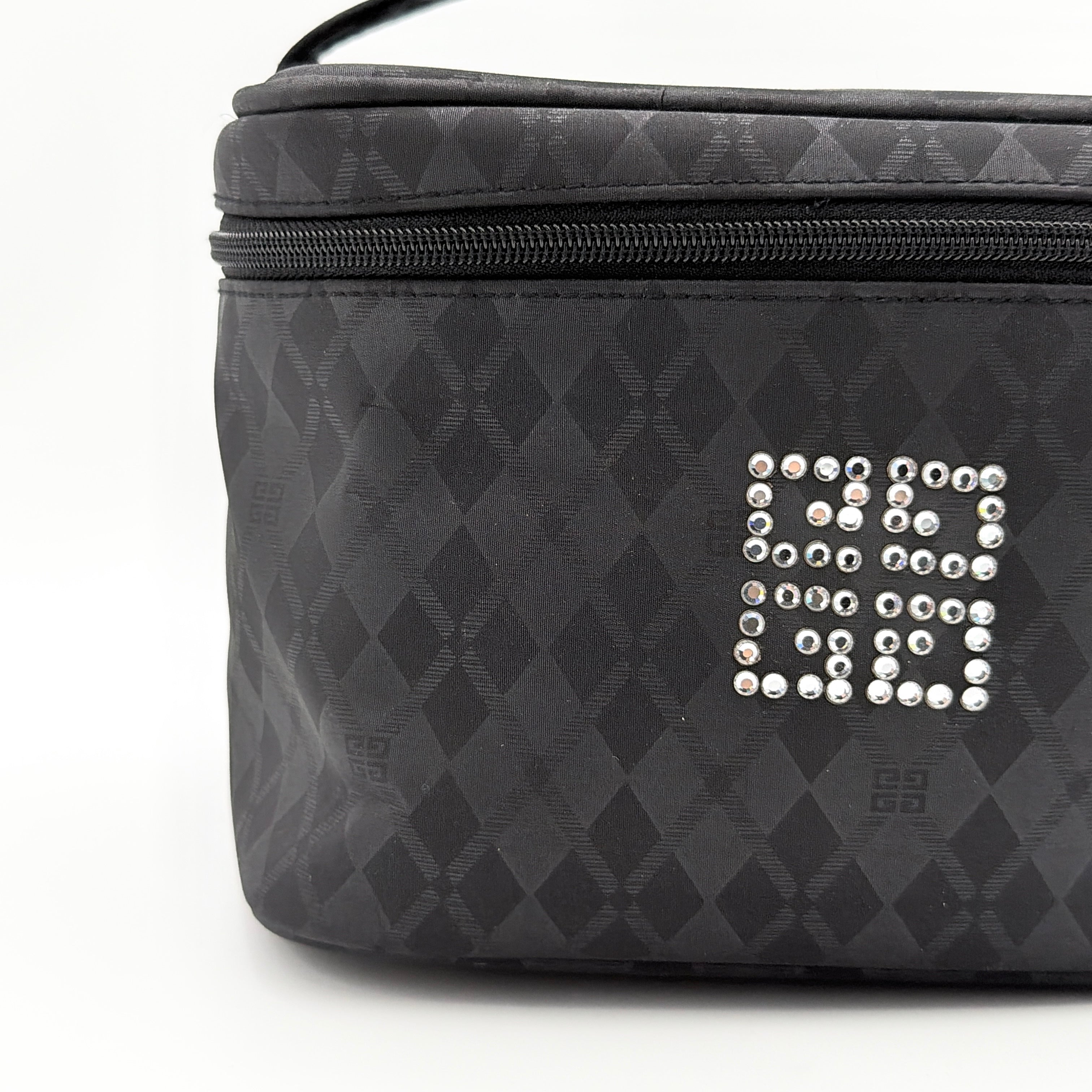 Givenchy vanity bag in black with rhinestone logo, geometric pattern, and top handle, shown from the front.