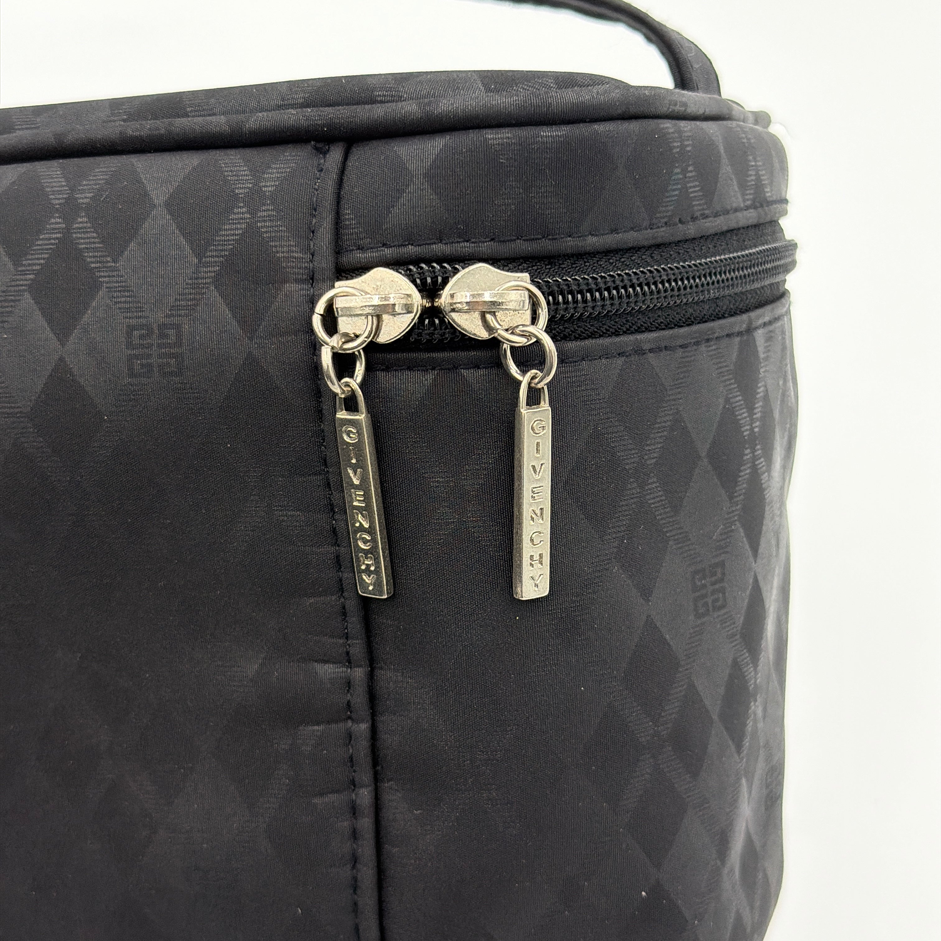 Givenchy vanity bag in black with rhinestone logo, geometric pattern, and top handle, shown from the front.