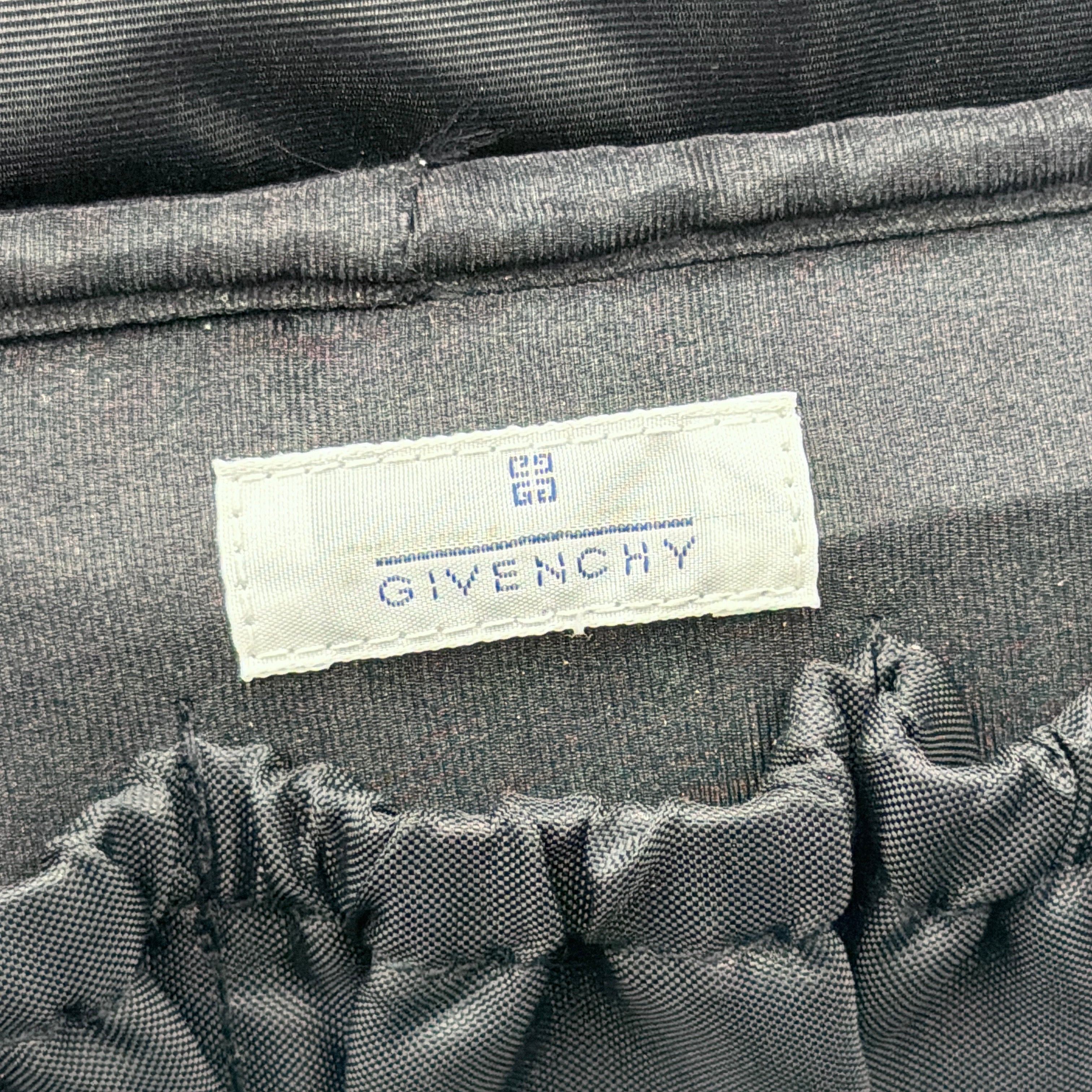 Givenchy vanity bag in black with rhinestone logo, geometric pattern, and top handle, shown from the front.