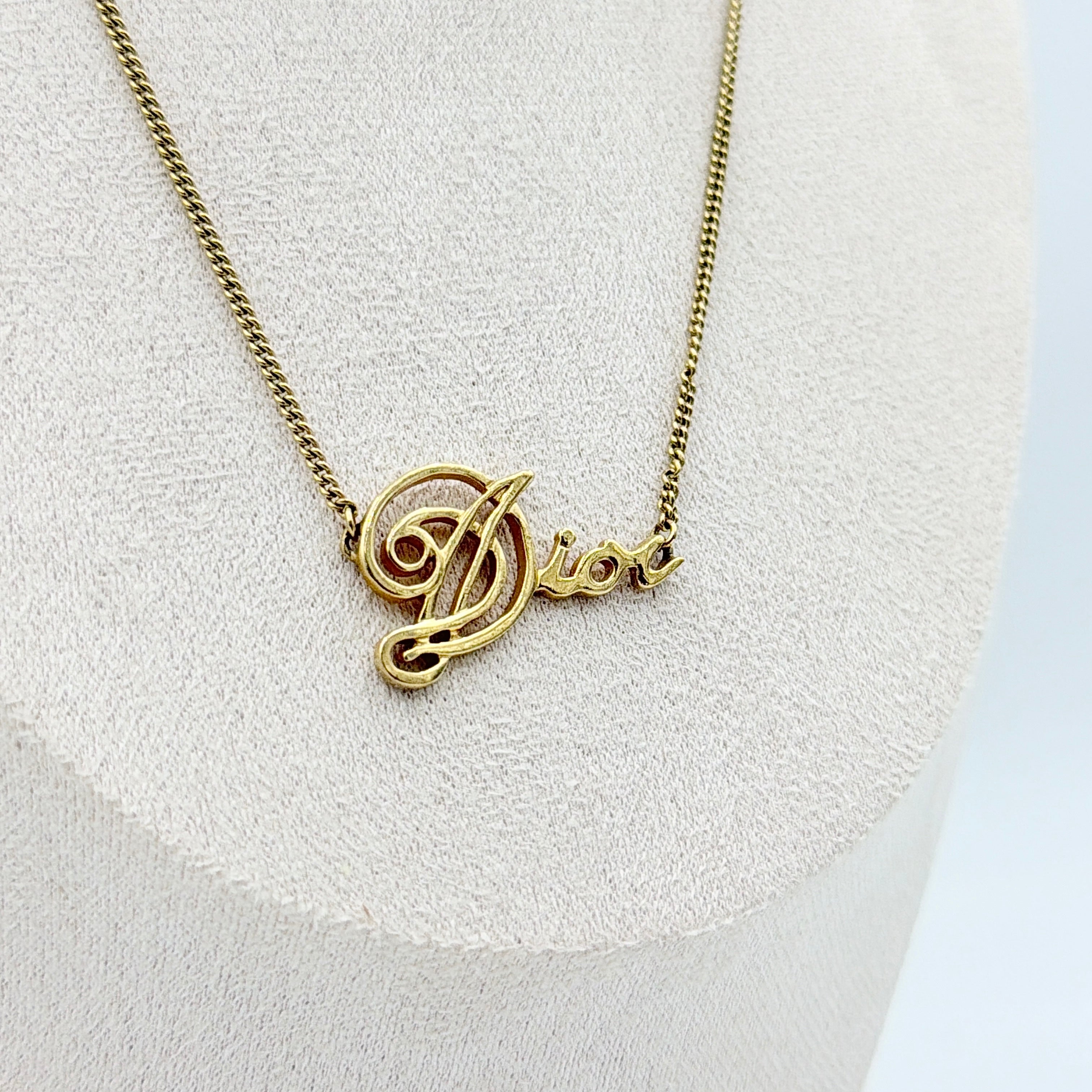 Dior gold logo letter necklace featuring an elegant script pendant on a fine gold chain.