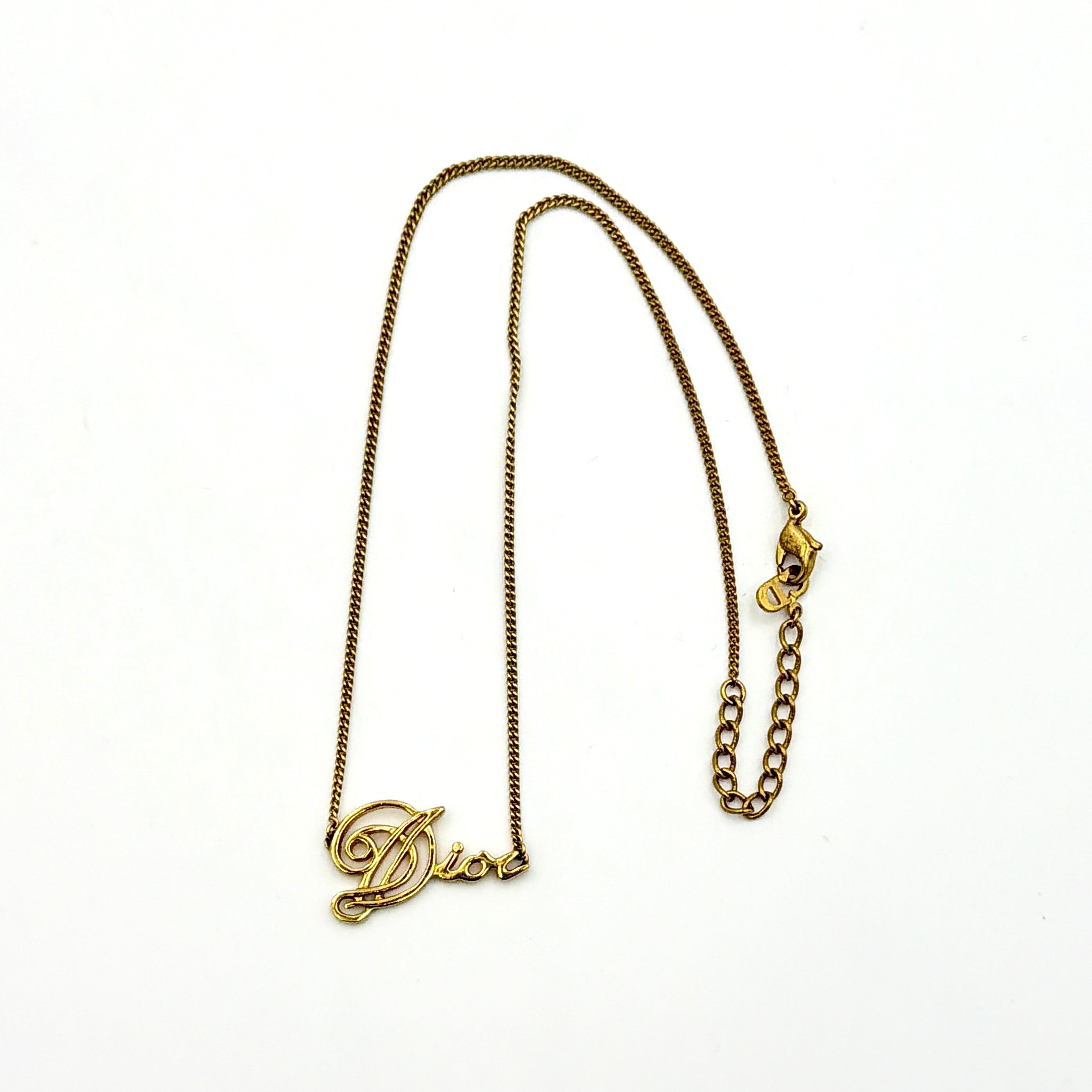 Dior gold logo letter necklace featuring an elegant script pendant on a fine gold chain.