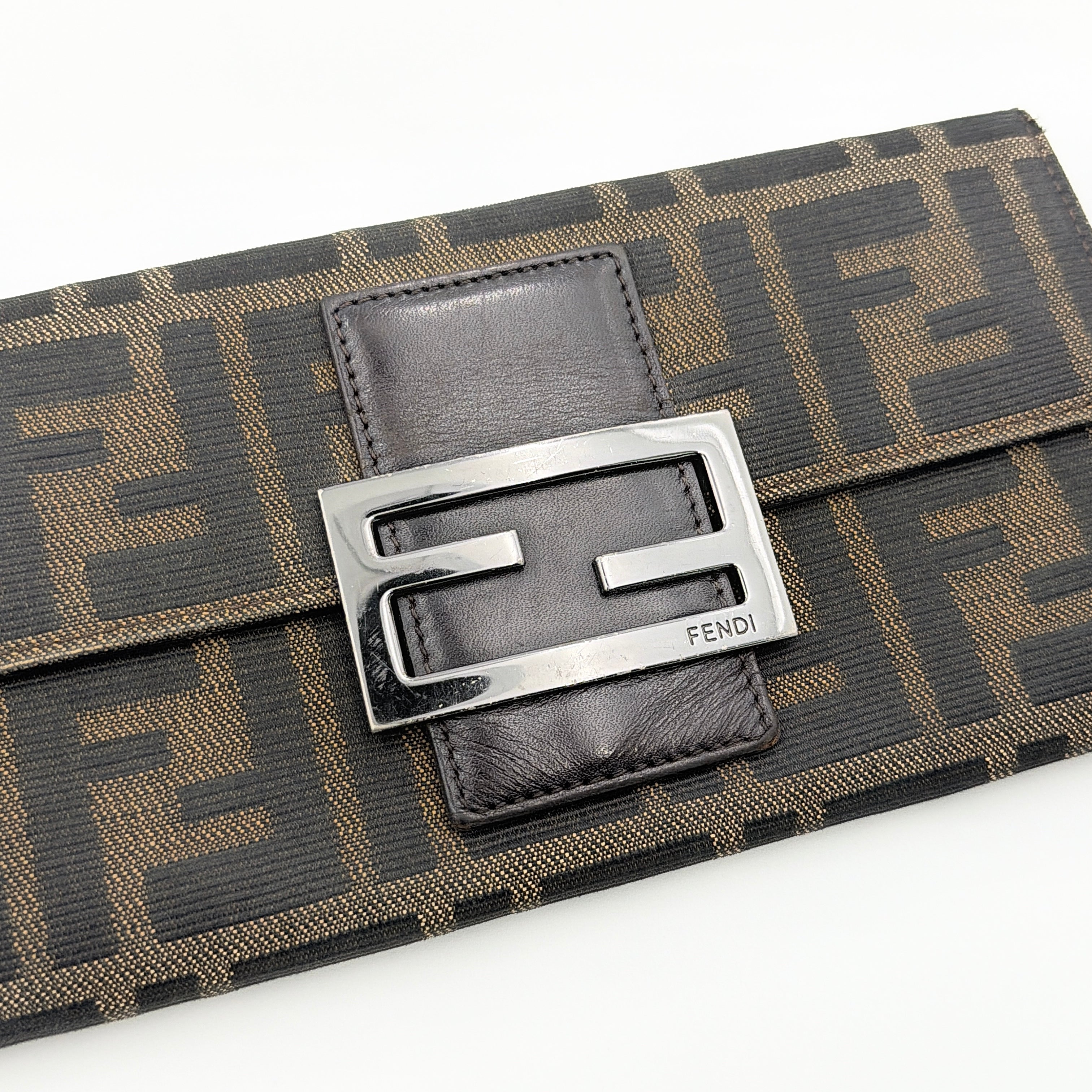 Front view of the Fendi FF Zucca long wallet in brown with signature monogram canvas and silver logo buckle.