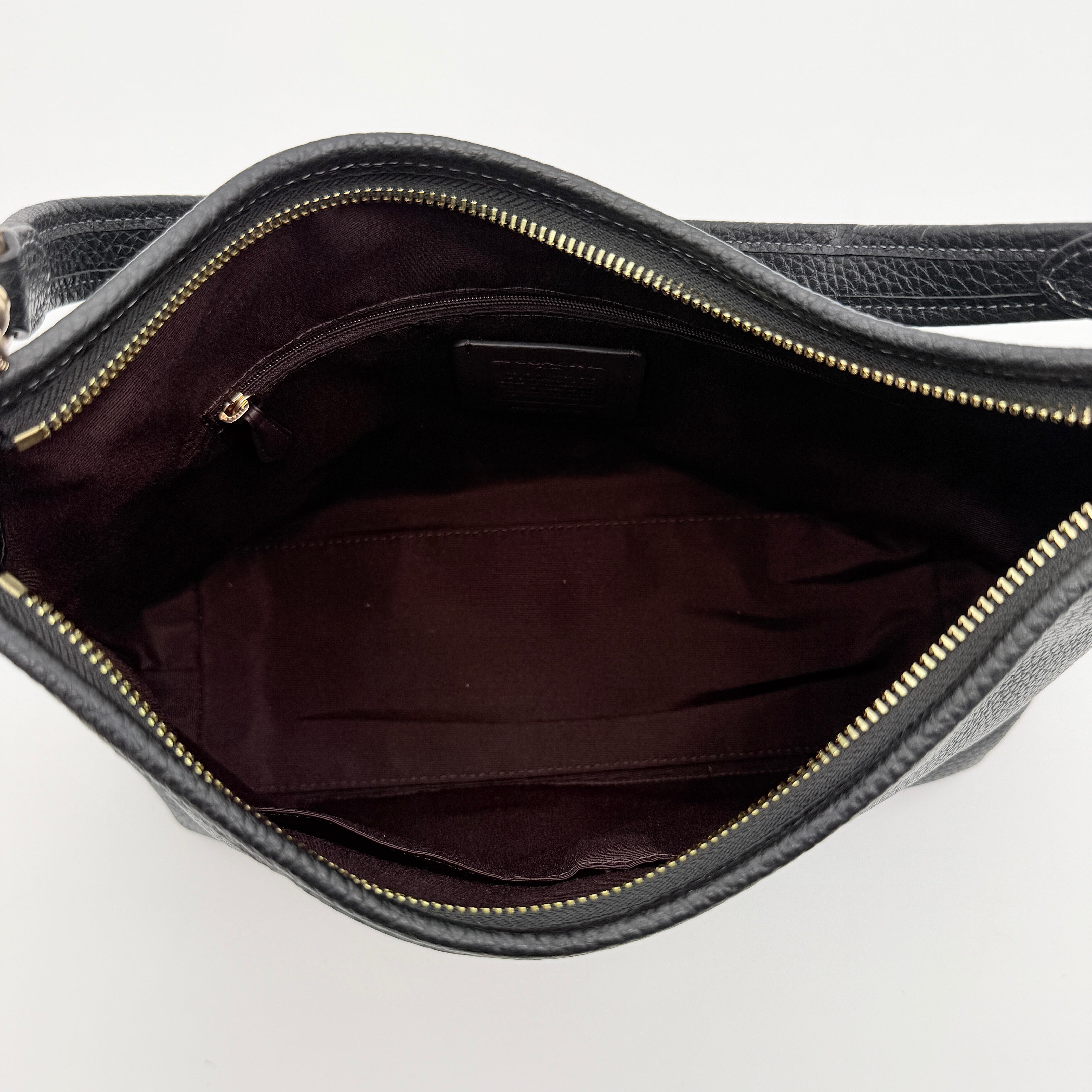 Coach Signature Laurel Shoulder Bag in black pebbled leather with gold hardware and a top zip closure.