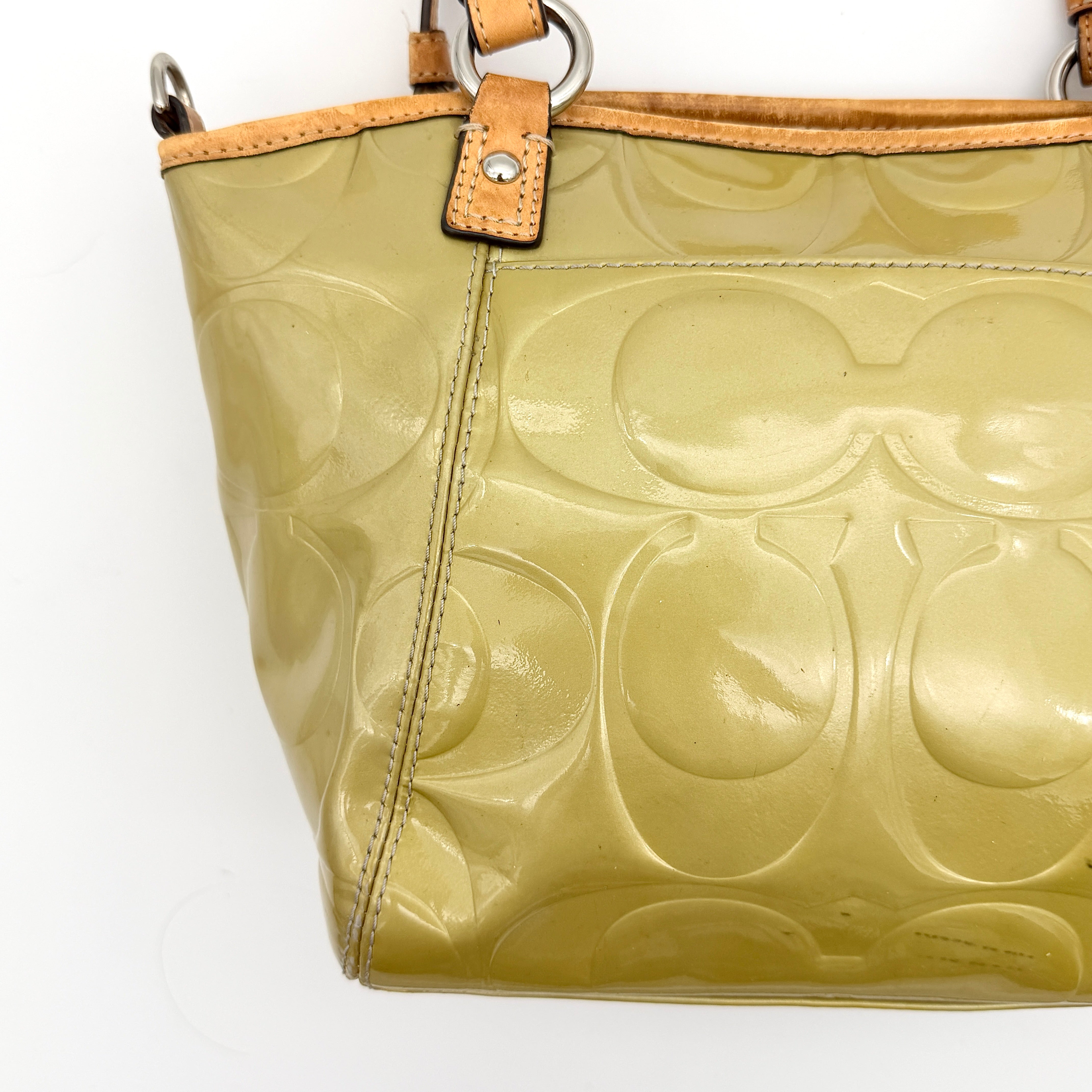 Coach Peyton embossed patent shoulder bag in yellow with tan leather trim and double handles, shown against a white background.