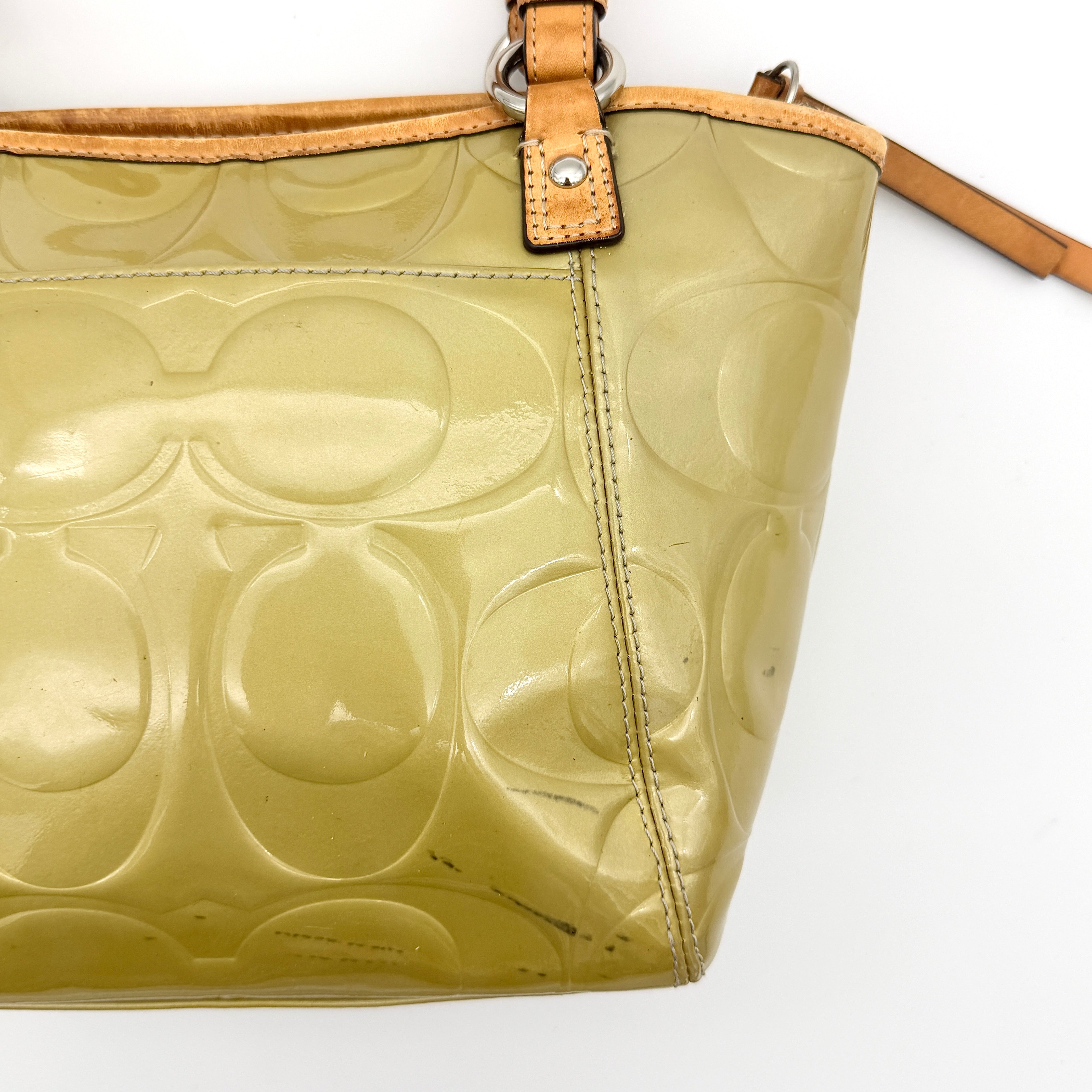 Coach Peyton embossed patent shoulder bag in yellow with tan leather trim and double handles, shown against a white background.