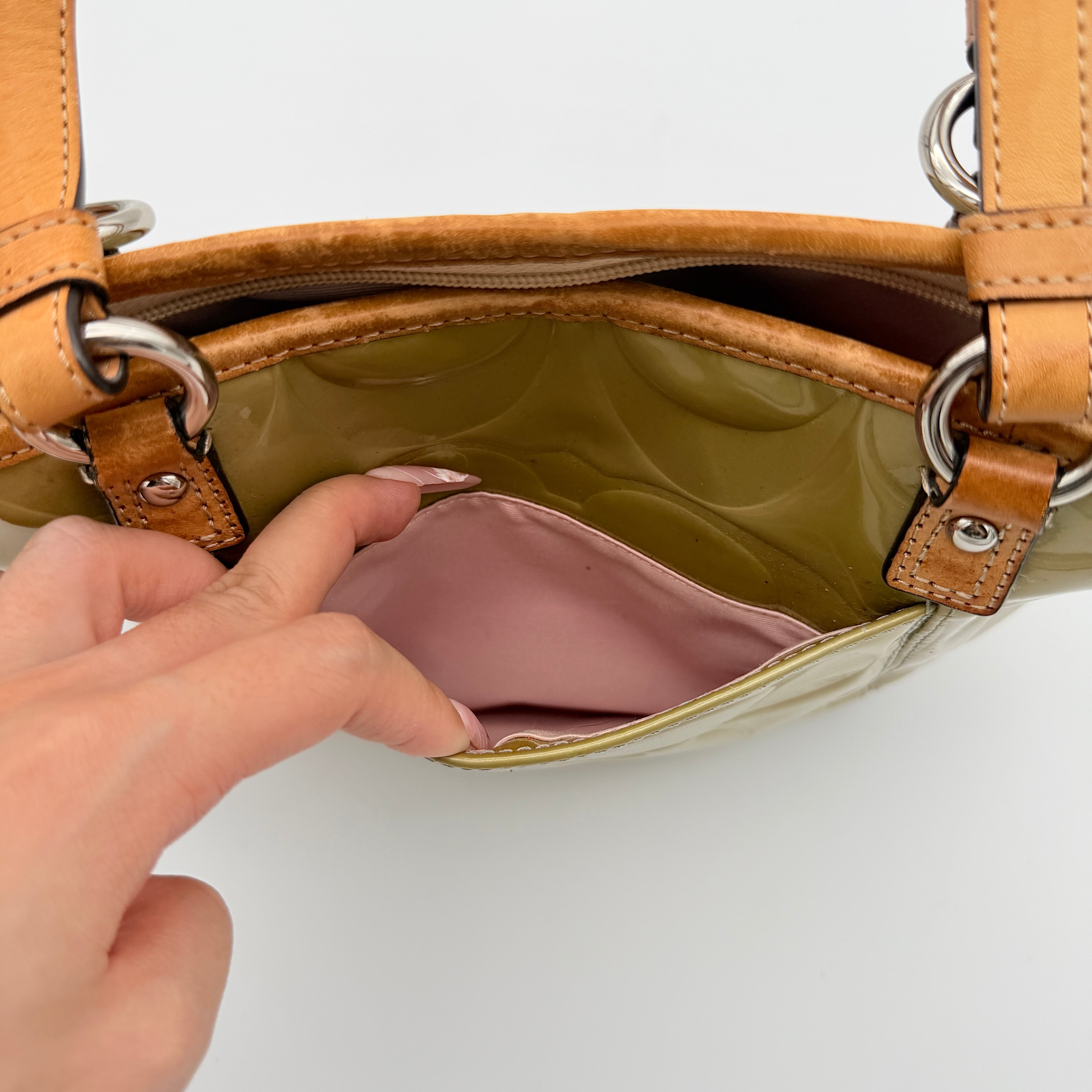 Coach Peyton embossed patent shoulder bag in yellow with tan leather trim and double handles, shown against a white background.