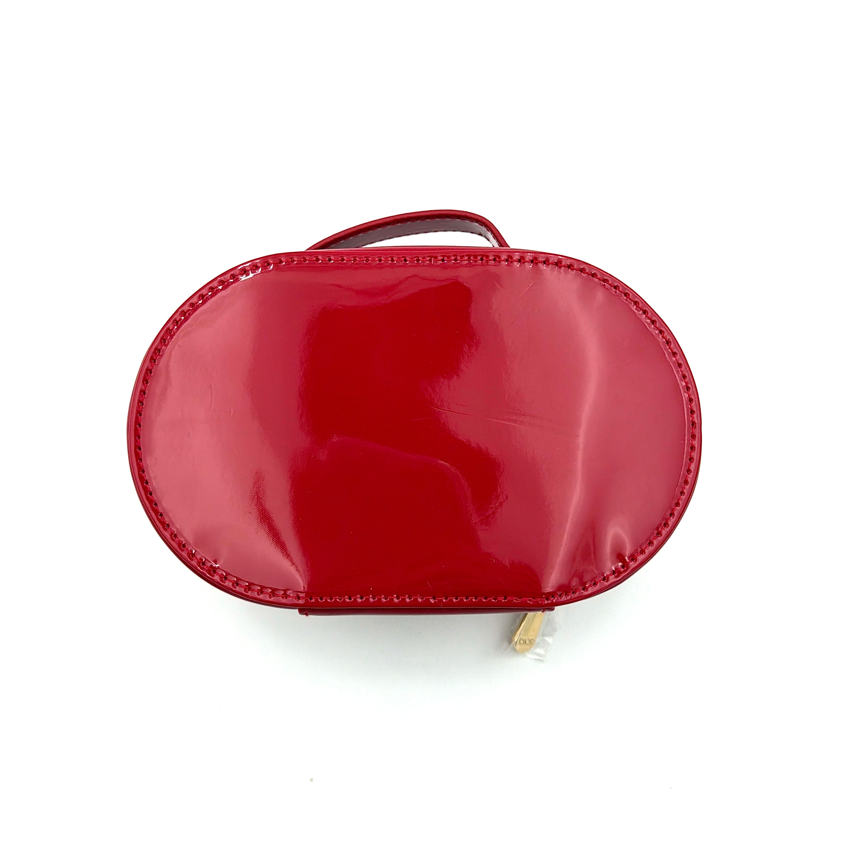 Christian Dior patent leather cosmetic pouch in glossy red with embossed DIOR logo and gold zip hardware.