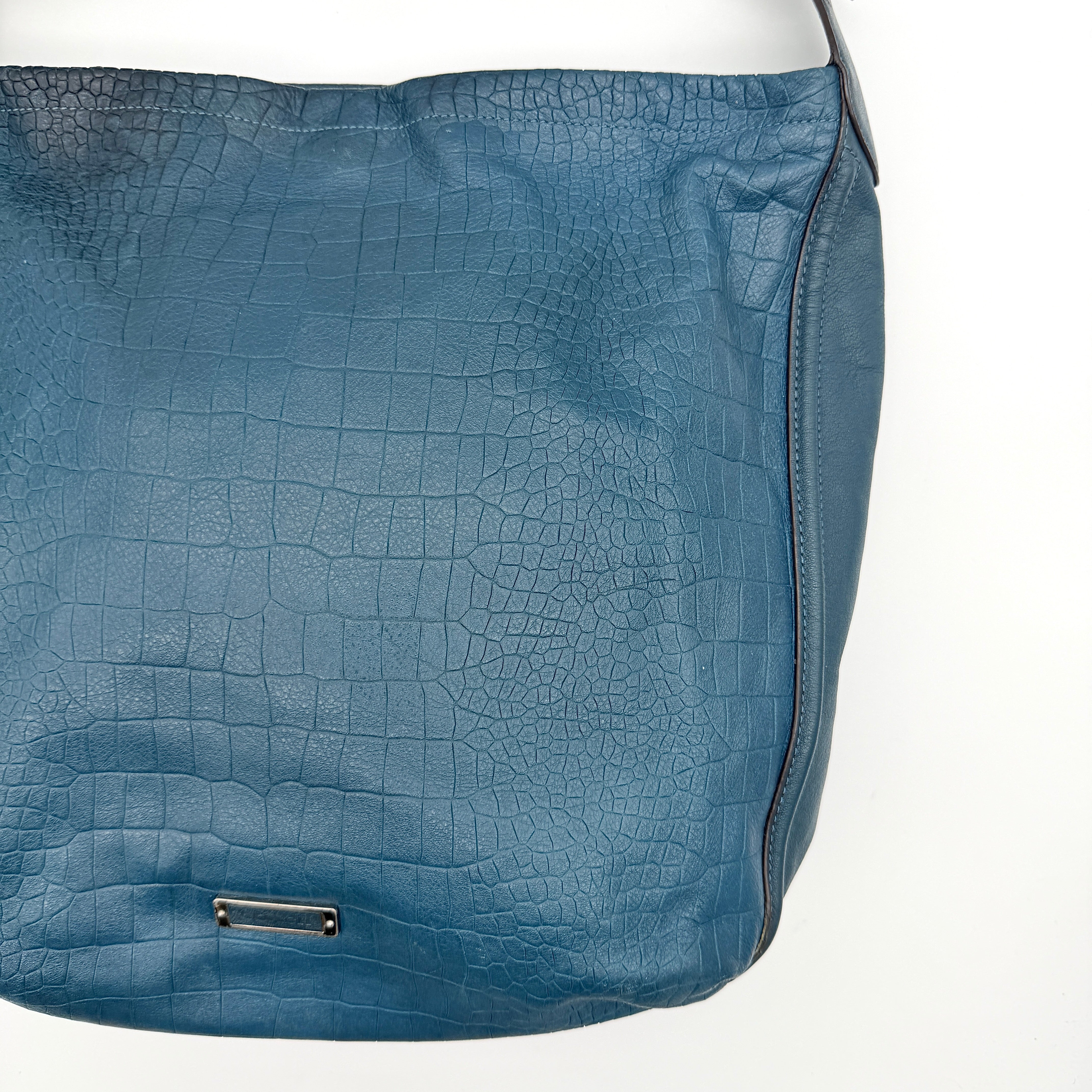 Coach Avery croc-embossed blue leather hobo shoulder bag with single handle and silver hardware against a white background.
