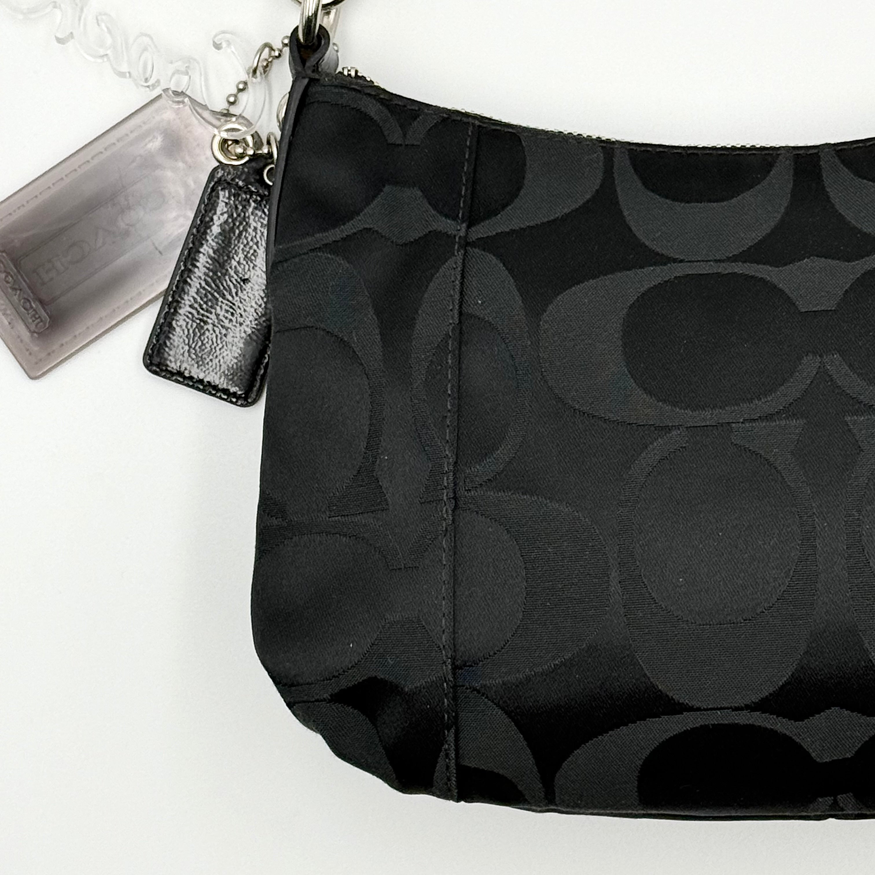 Coach black Signature Poppy Shoulder Bag with silver hardware, Coach tags, and tonal jacquard finish on a white background.