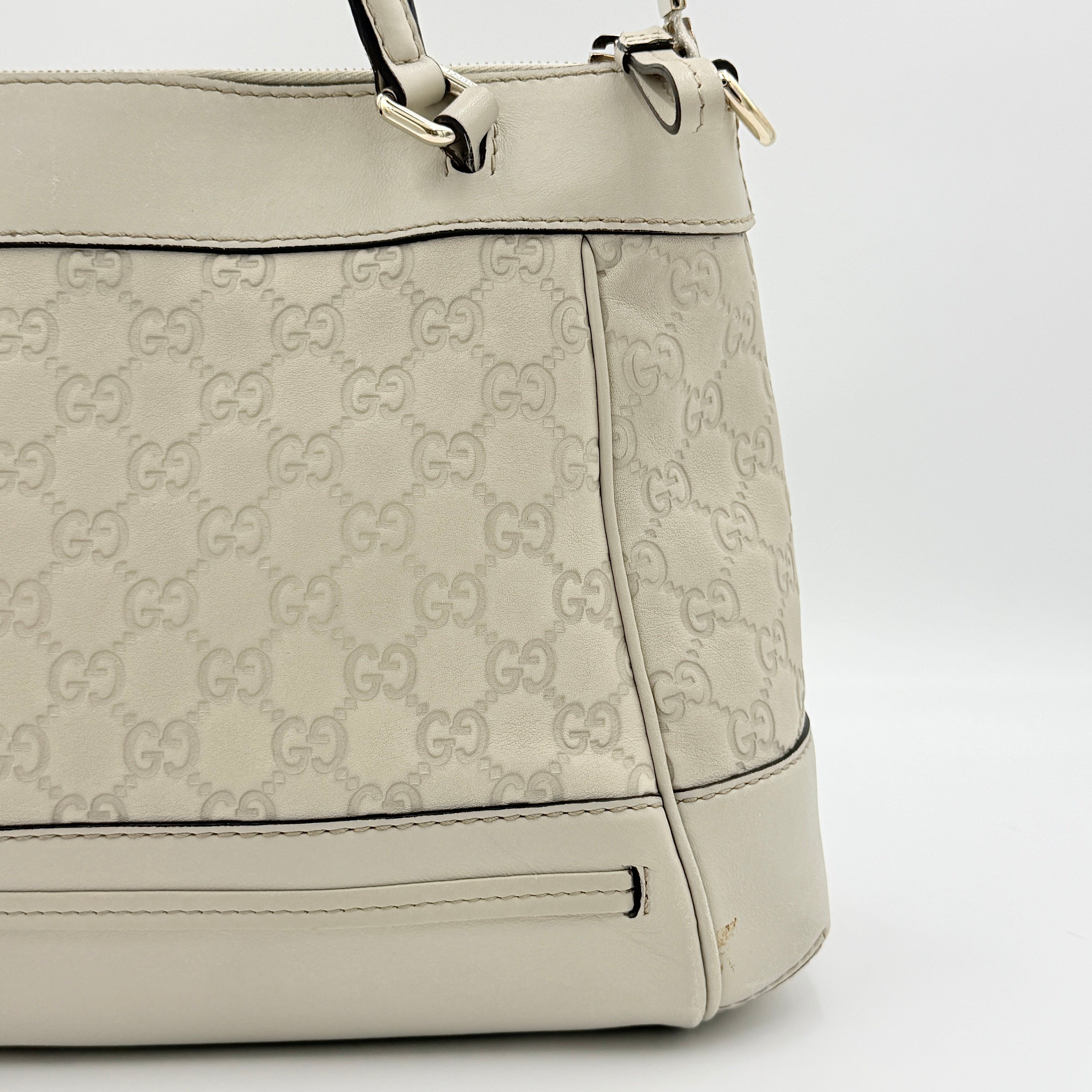 Gucci Mayfair Bow 2Way shoulder bag in cream GG monogram leather with dual handles and detachable strap, styled against a neutral backdrop.
