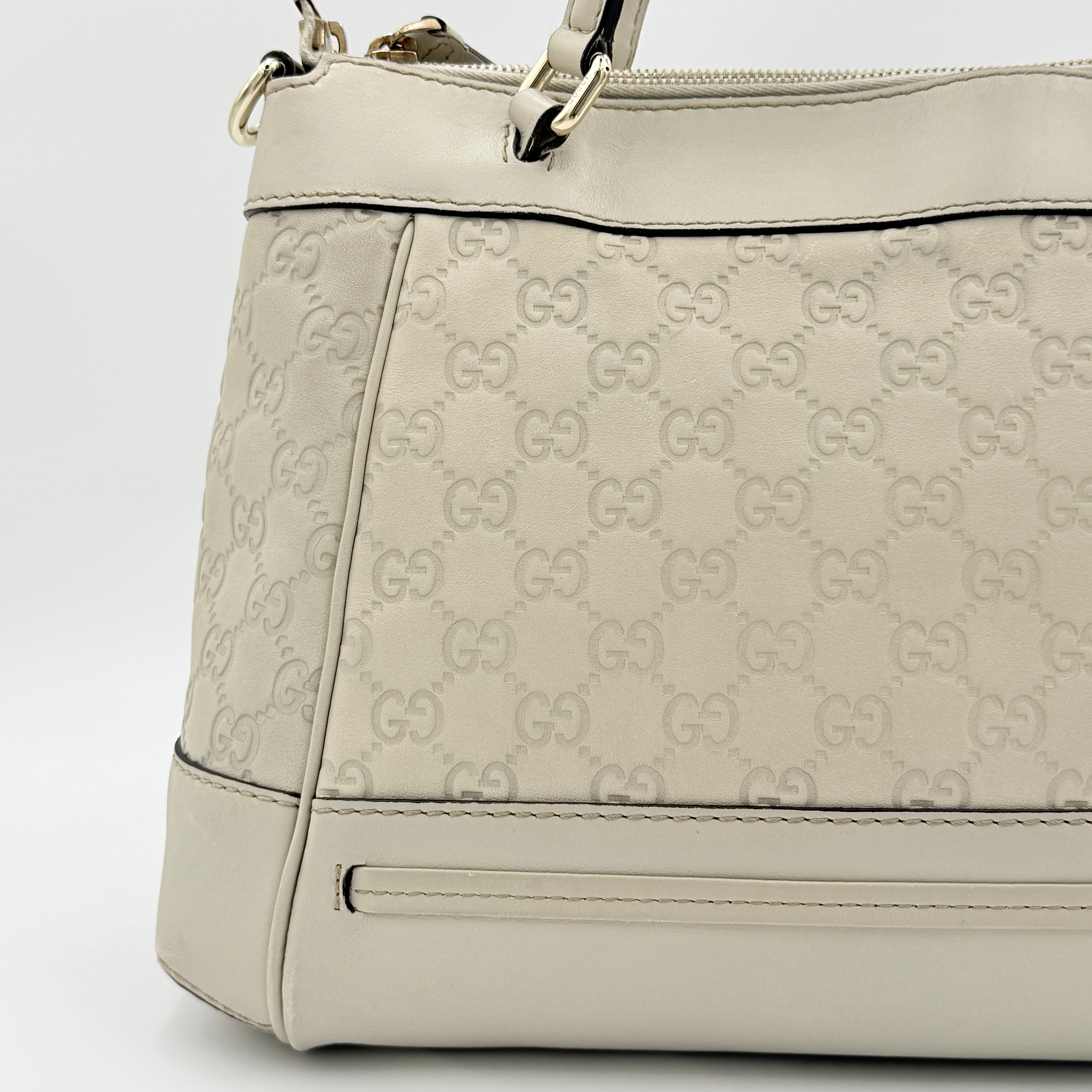 Gucci Mayfair Bow 2Way shoulder bag in cream GG monogram leather with dual handles and detachable strap, styled against a neutral backdrop.