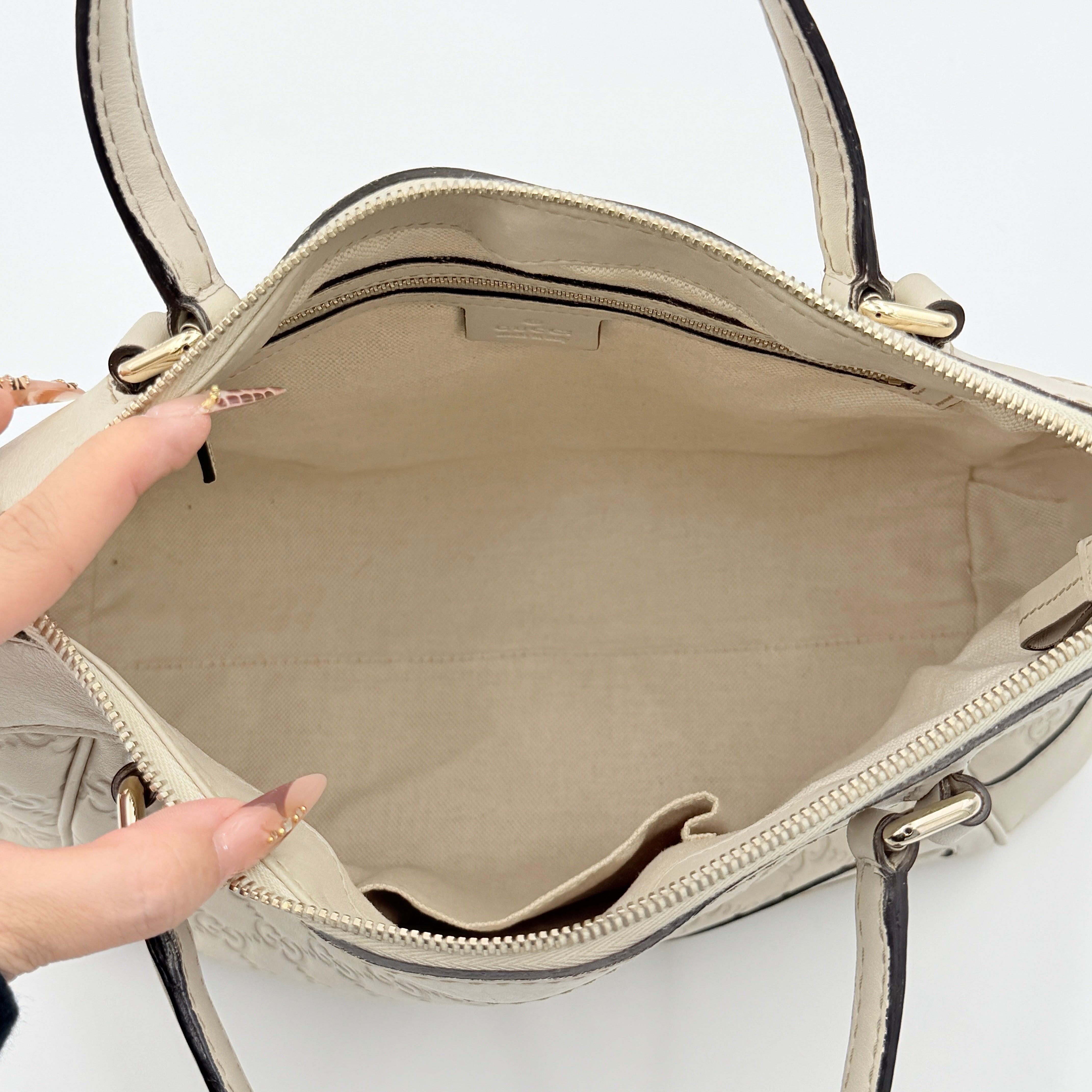 Gucci Mayfair Bow 2Way shoulder bag in cream GG monogram leather with dual handles and detachable strap, styled against a neutral backdrop.