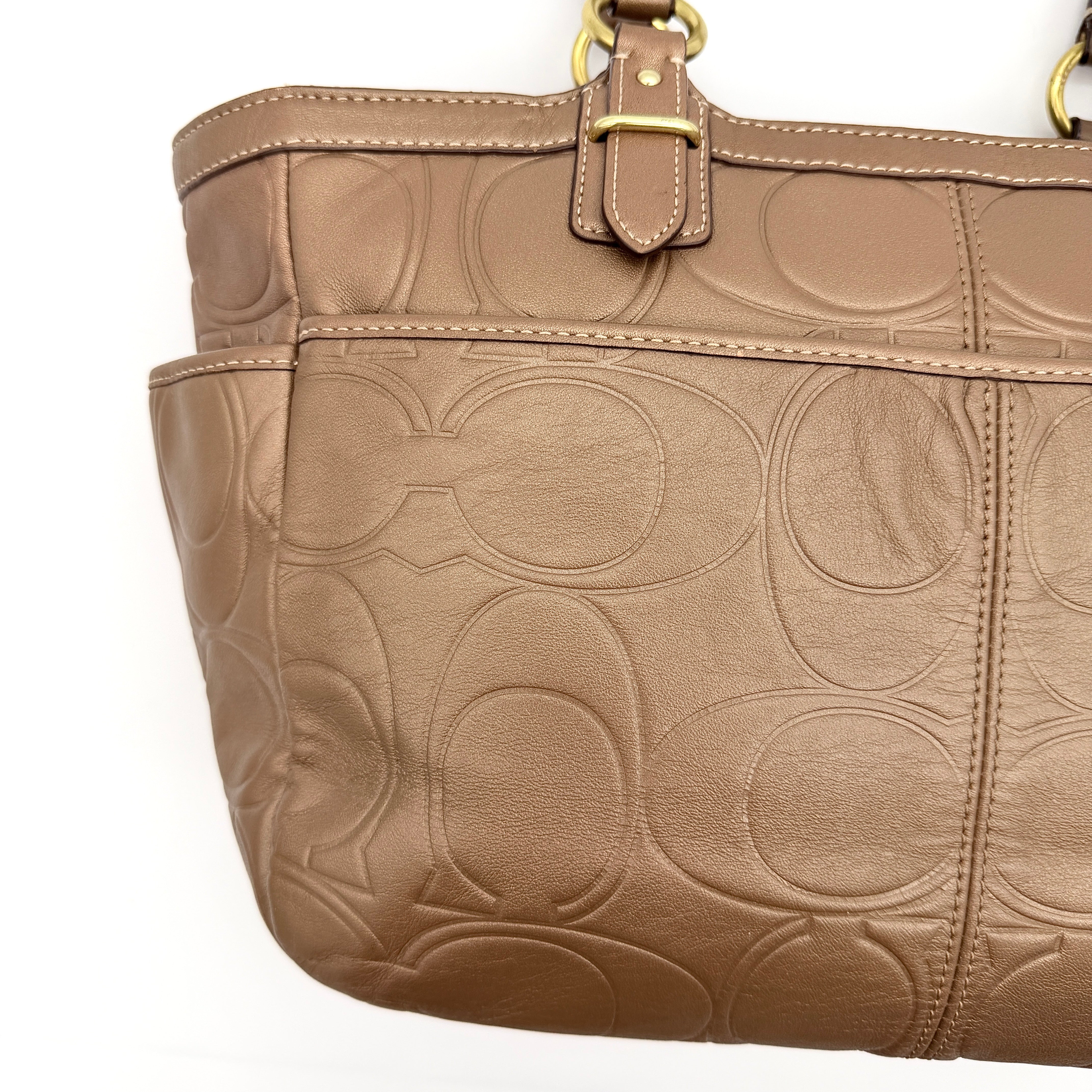 Coach Signature Gallery embossed leather tote bag in brown with gold tone hardware and dual handles.