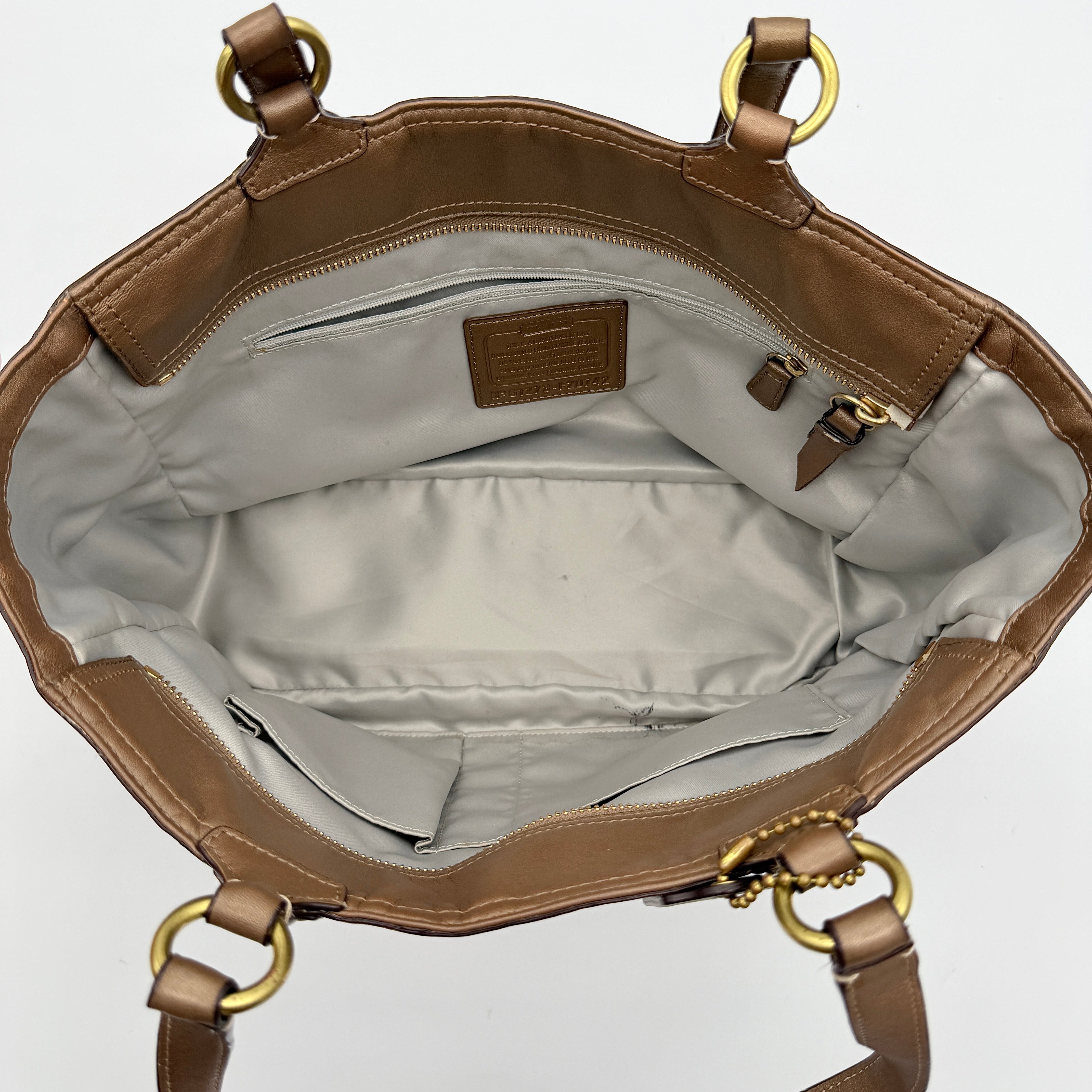 Coach Signature Gallery embossed leather tote bag in brown with gold tone hardware and dual handles.