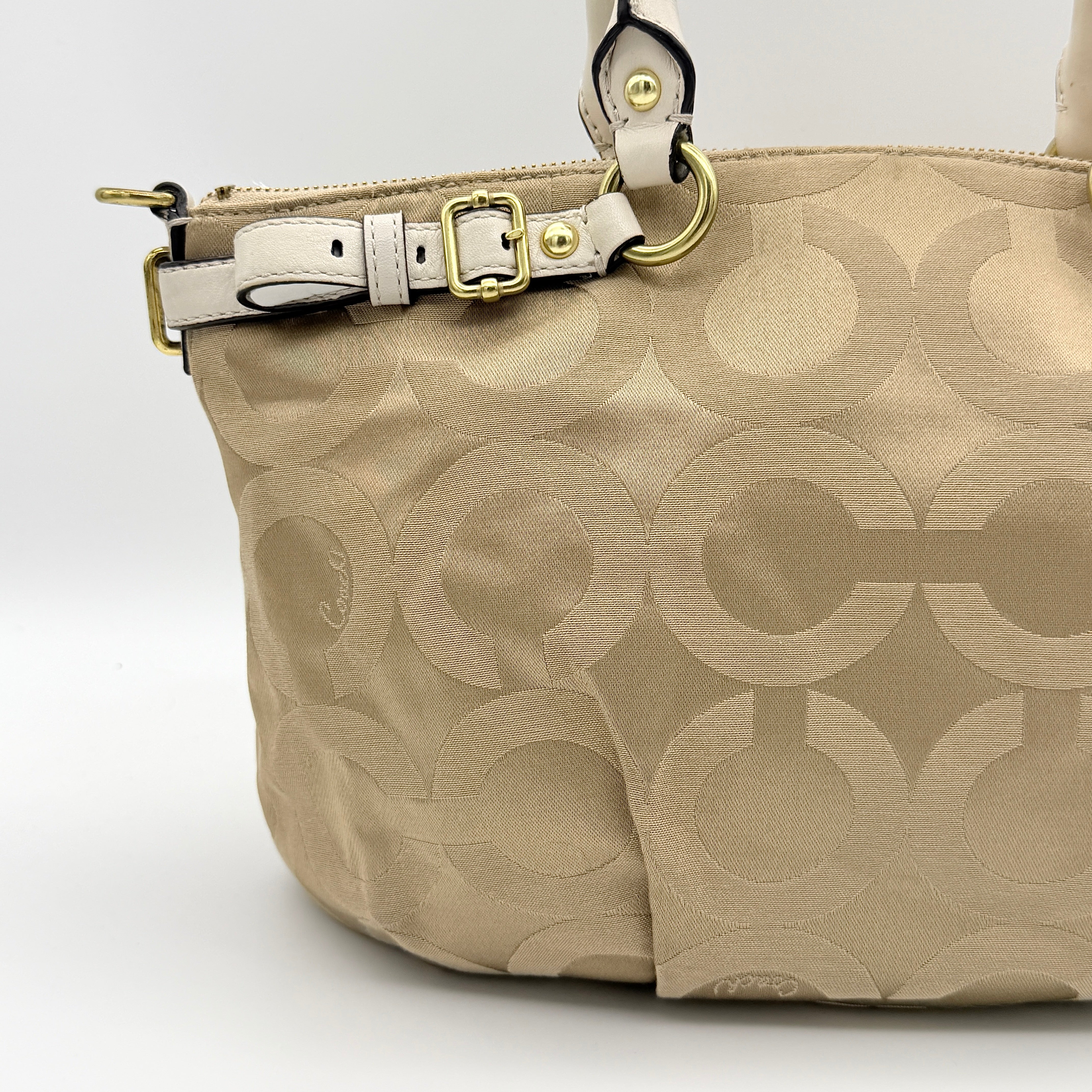 Beige Coach Madison Op Art Sophia shoulder bag with ivory leather handles, gold hardware, and detachable strap.