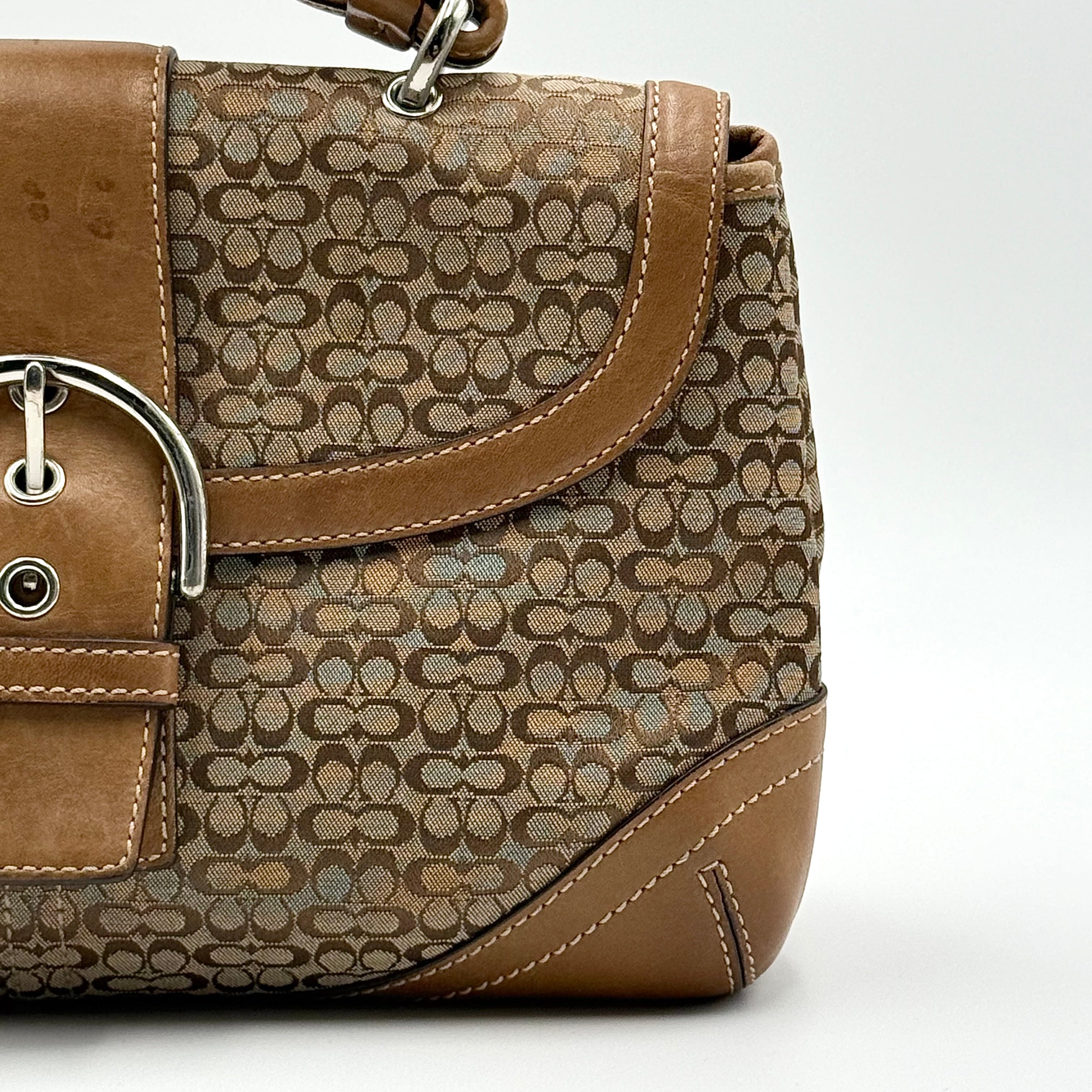 Coach Signature Soho shoulder bag in beige and tan jacquard with leather trim and silver D-ring buckle, shown against a white background.