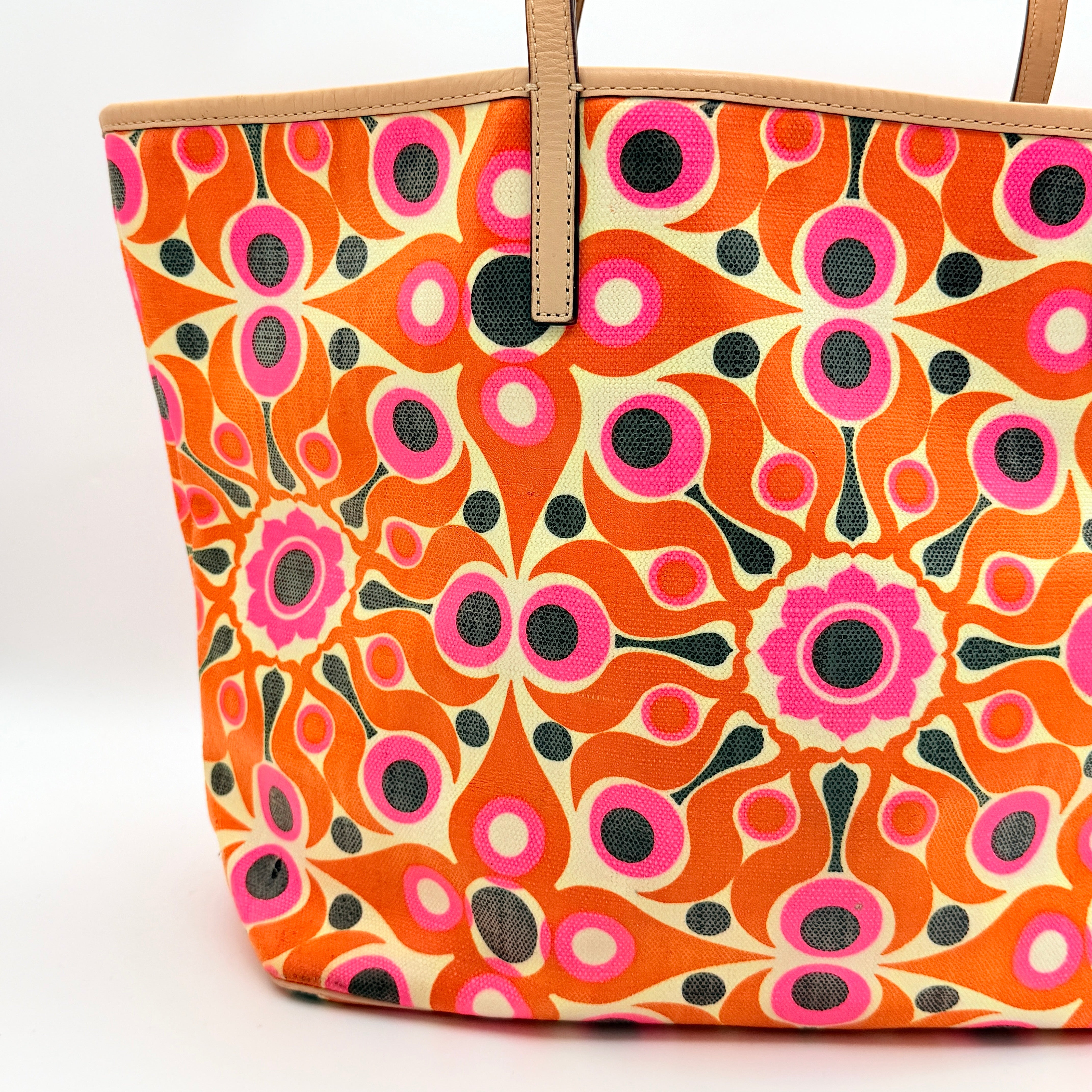 Kate Spade New York tote bag in a bold multicolour geometric pattern with beige leather handles, displayed upright against a white background.