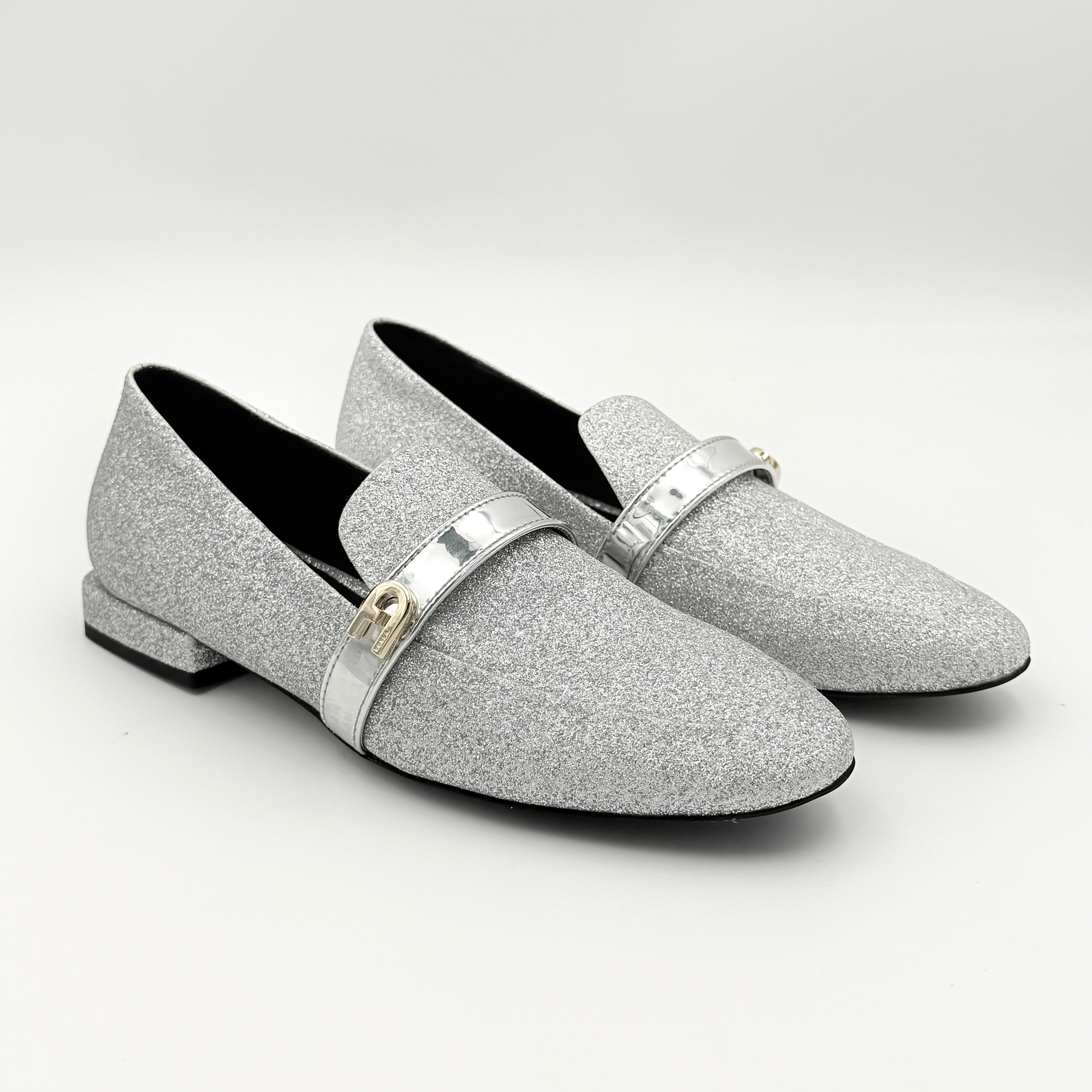 Furla 1927 T.20 loafers in silver microglitter with metallic strap and gold-tone detail, displayed in a three-quarter view.