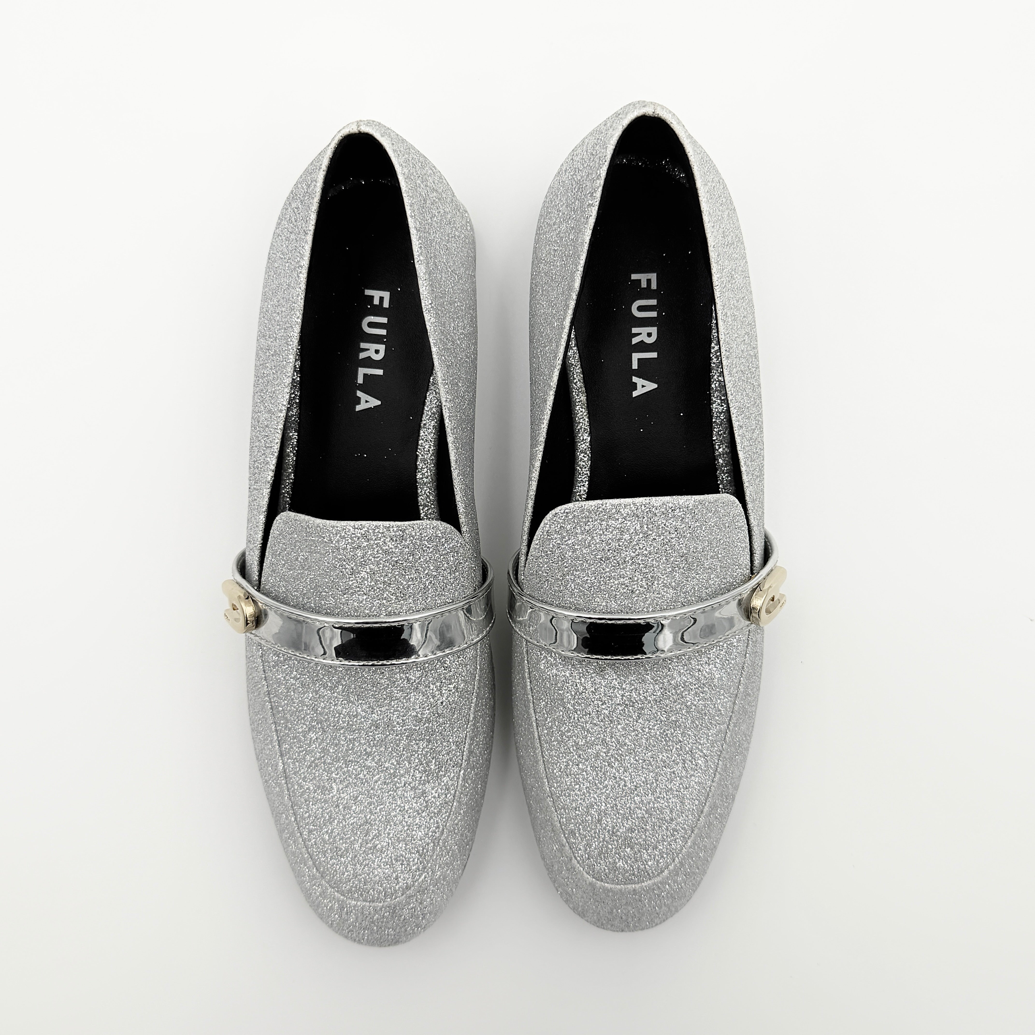 Furla 1927 T.20 loafers in silver microglitter with metallic strap and gold-tone detail, displayed in a three-quarter view.