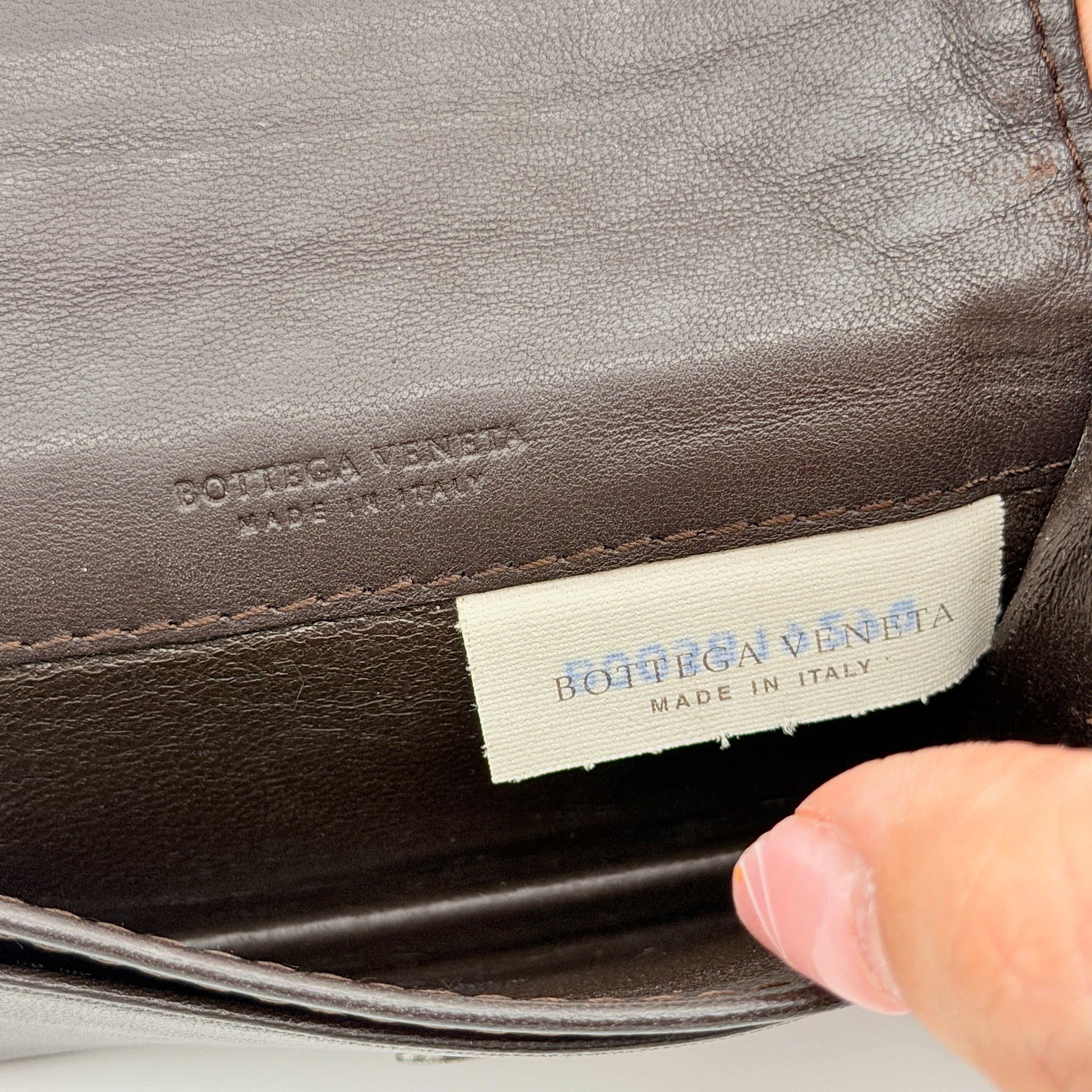 Bottega Veneta Intrecciato card case in black leather with woven front, photographed against a white background.