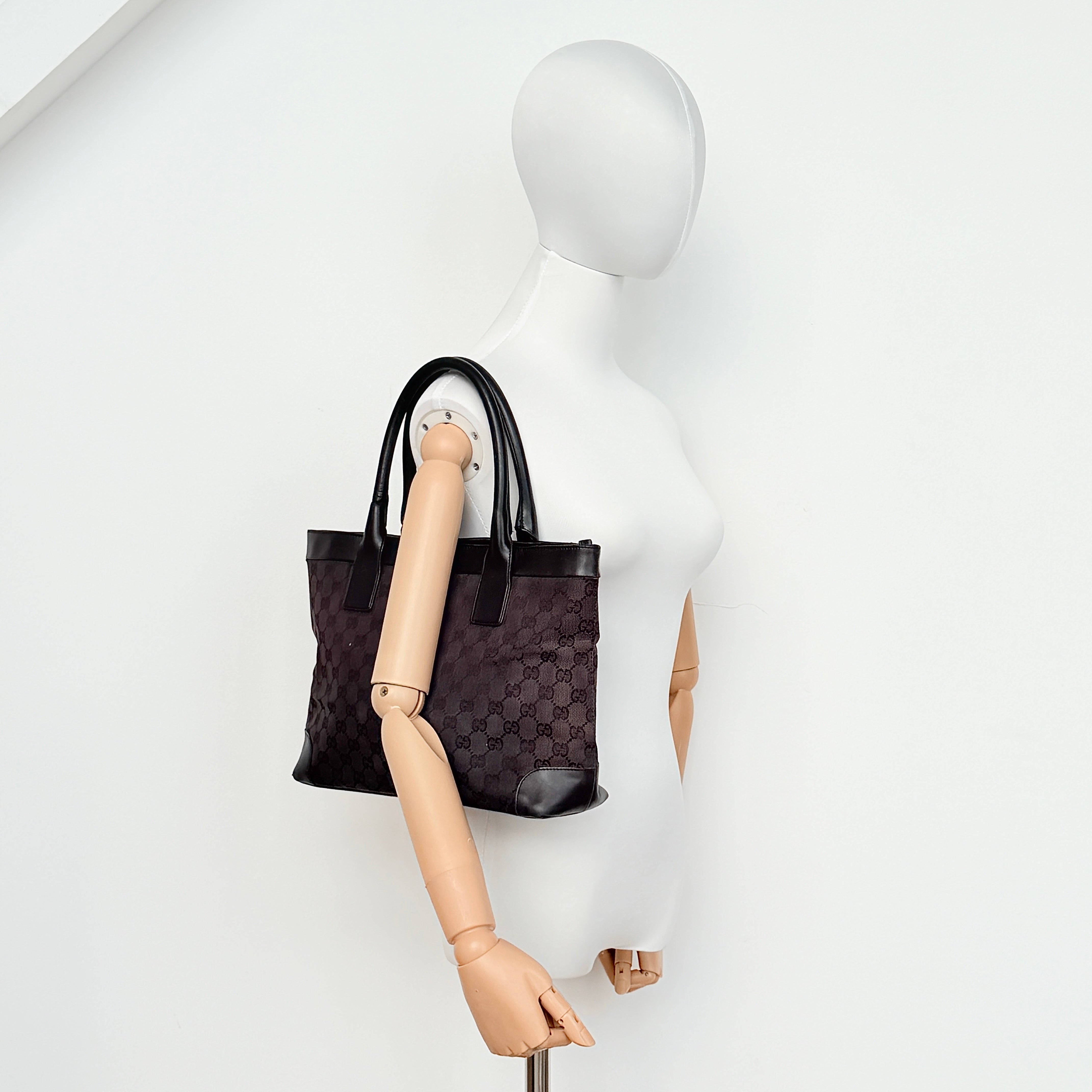 Gucci GG Monogram Leather Tote Bag in black canvas and leather, with structured top handles and allover GG motif.