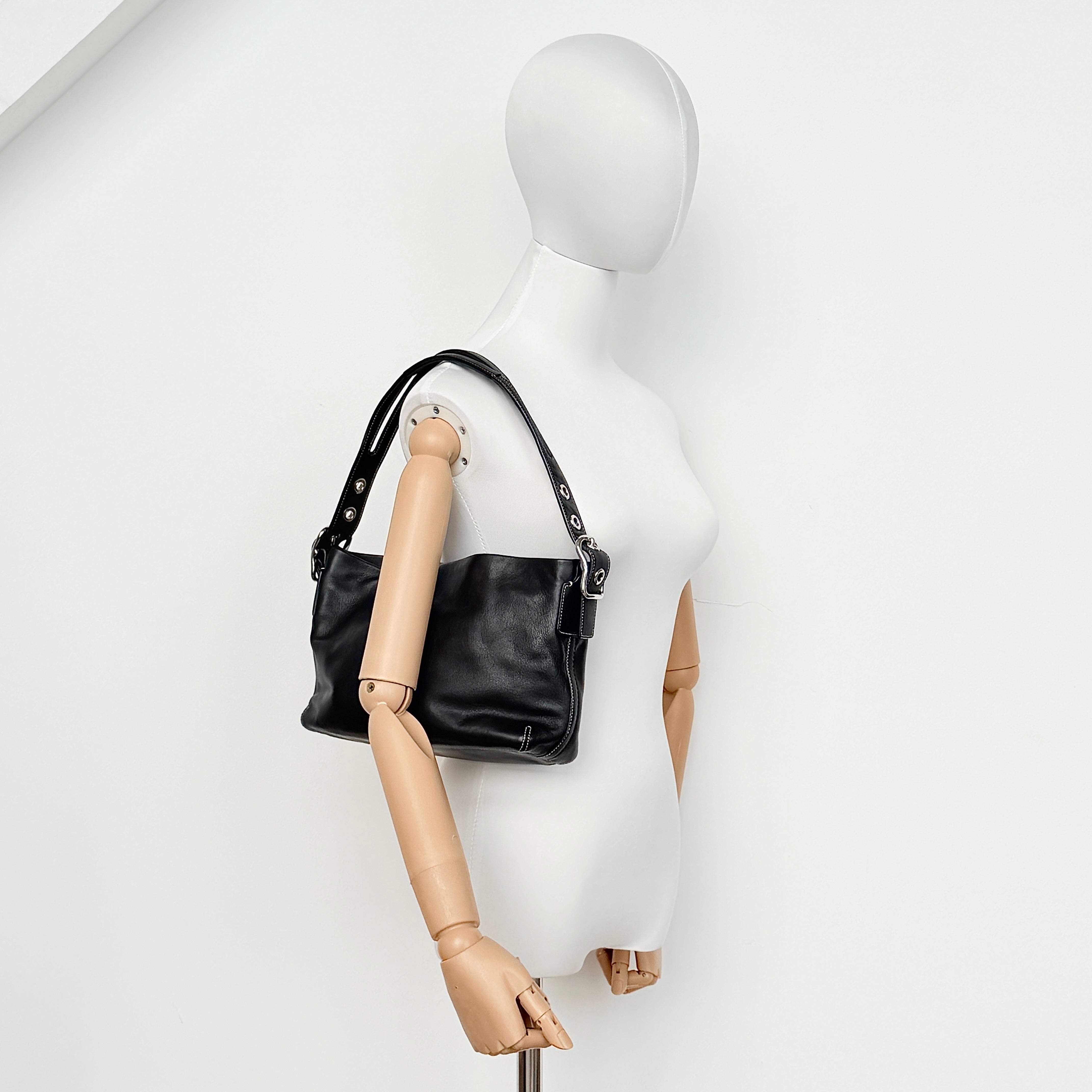 Coach Signature East West Shoulder Bag in black leather with silver hardware and contrast stitching, displayed on a white background.