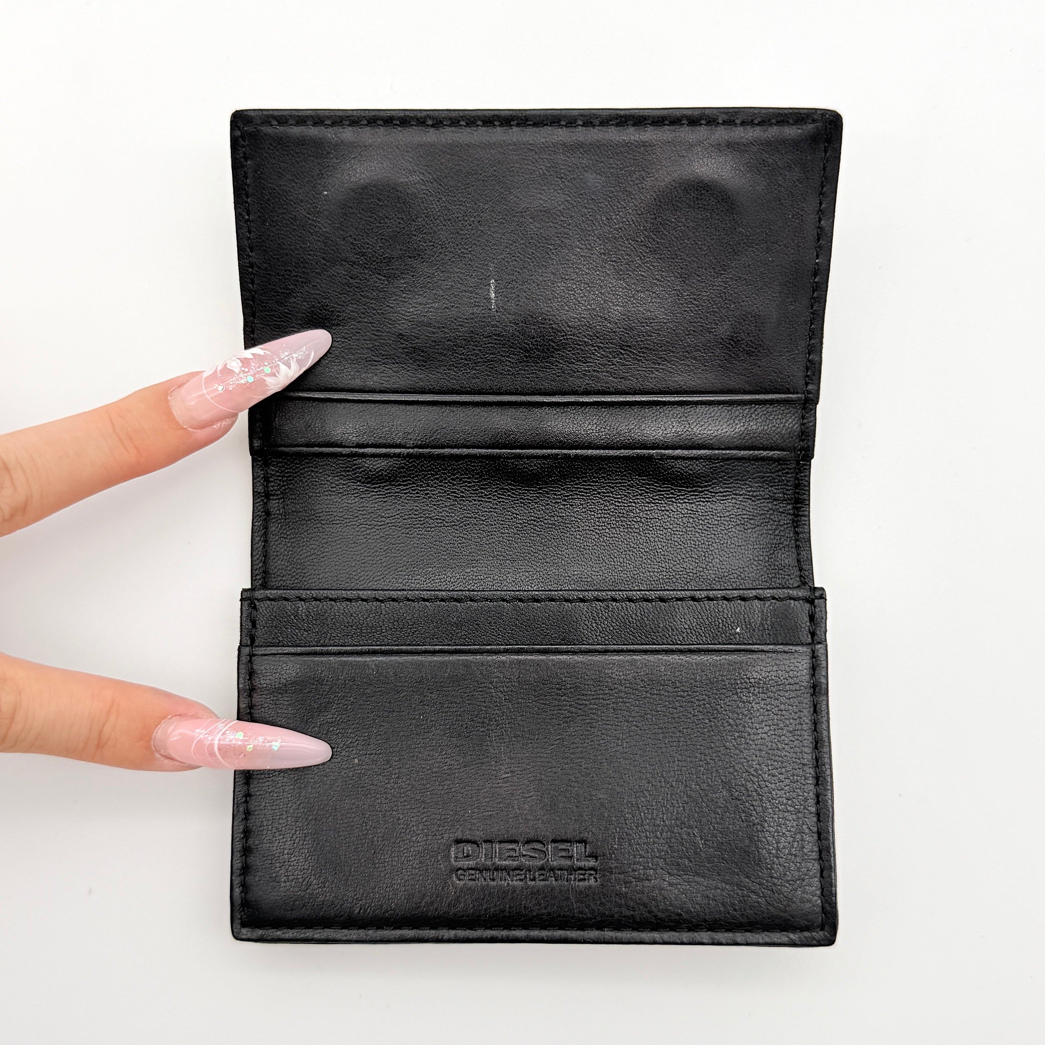 Diesel card case in white leather with bold black grommets and studs on the front.