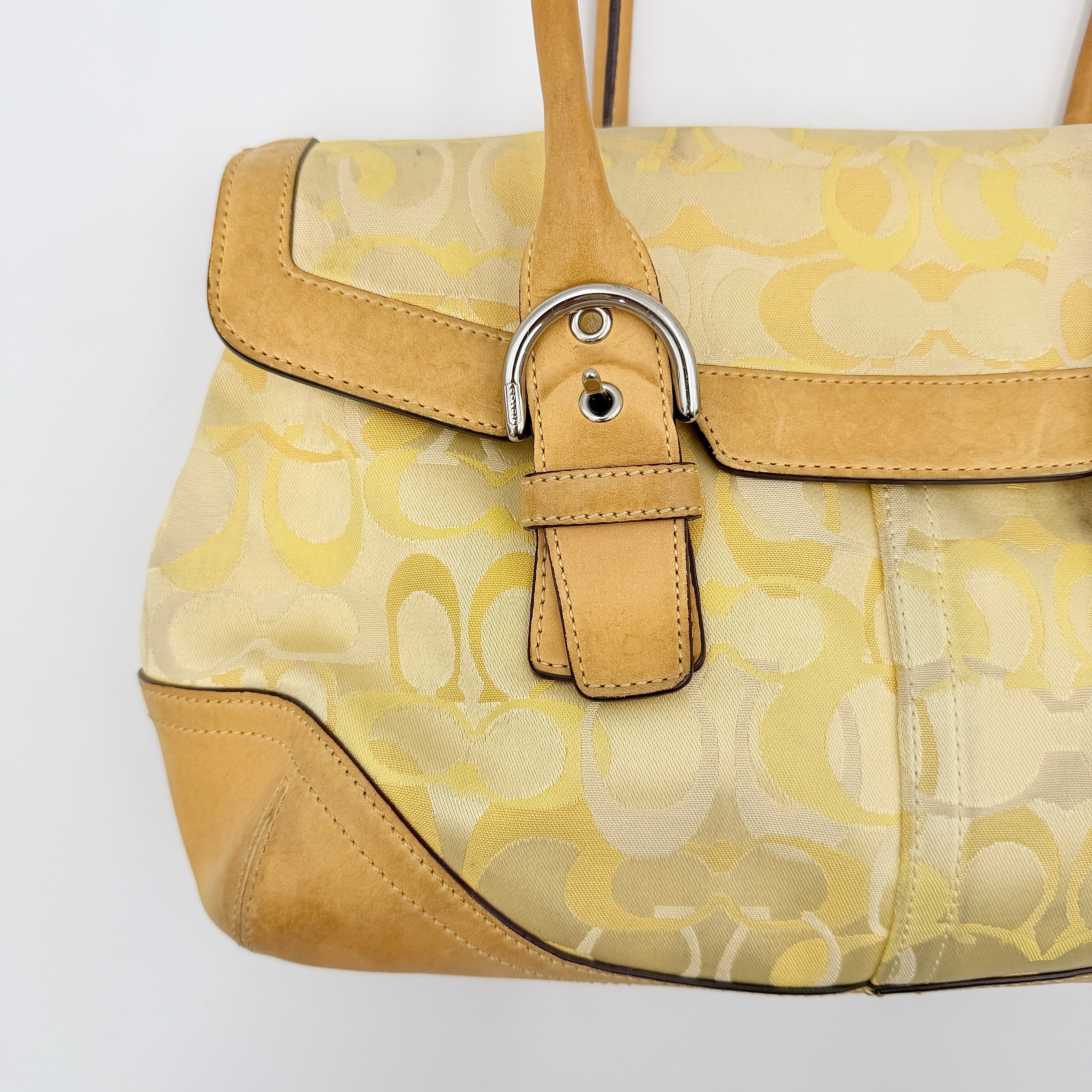 Coach Soho shoulder bag in yellow signature optic fabric with tan leather trim and silver hardware, shown with double handles.