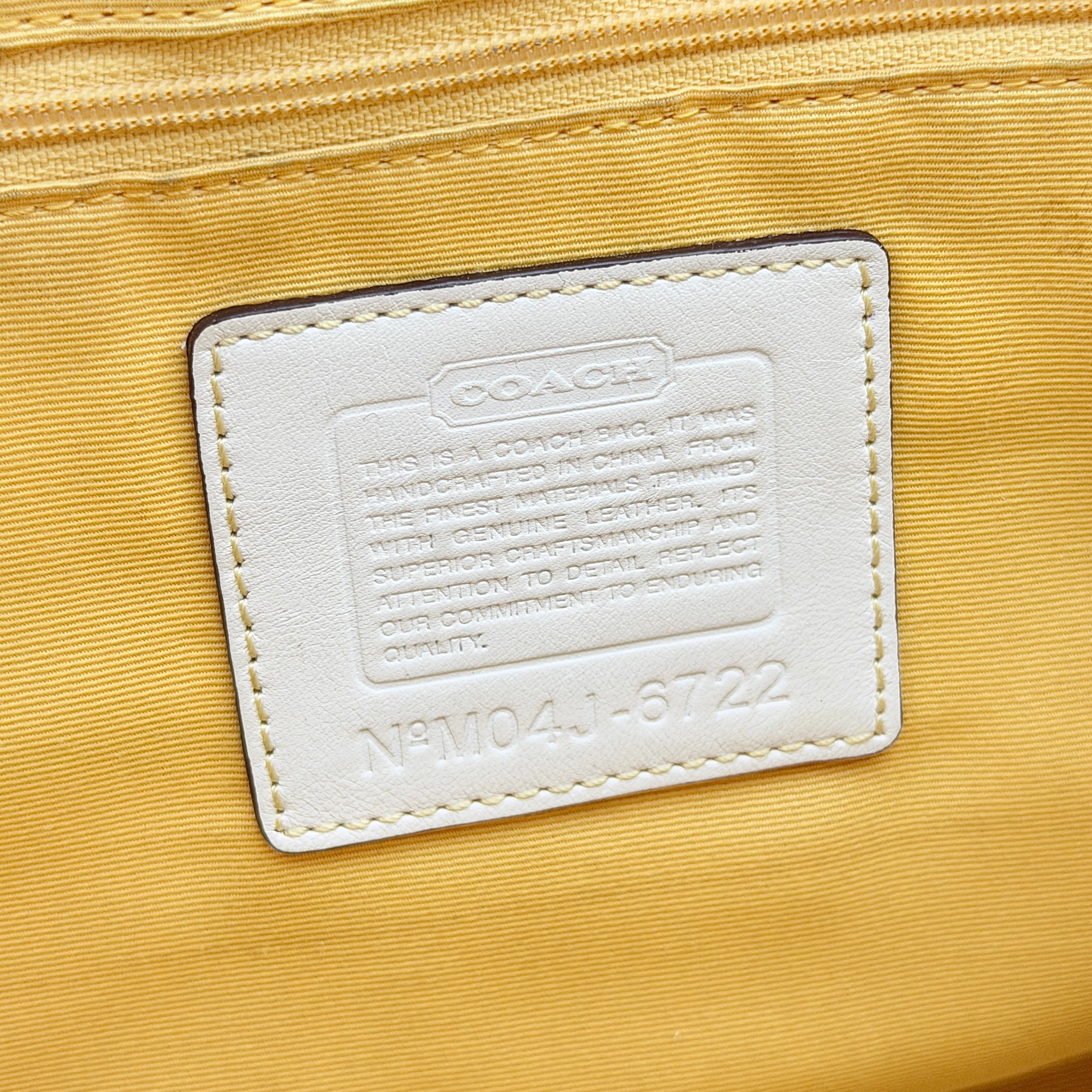 Coach Soho shoulder bag in yellow signature optic fabric with tan leather trim and silver hardware, shown with double handles.