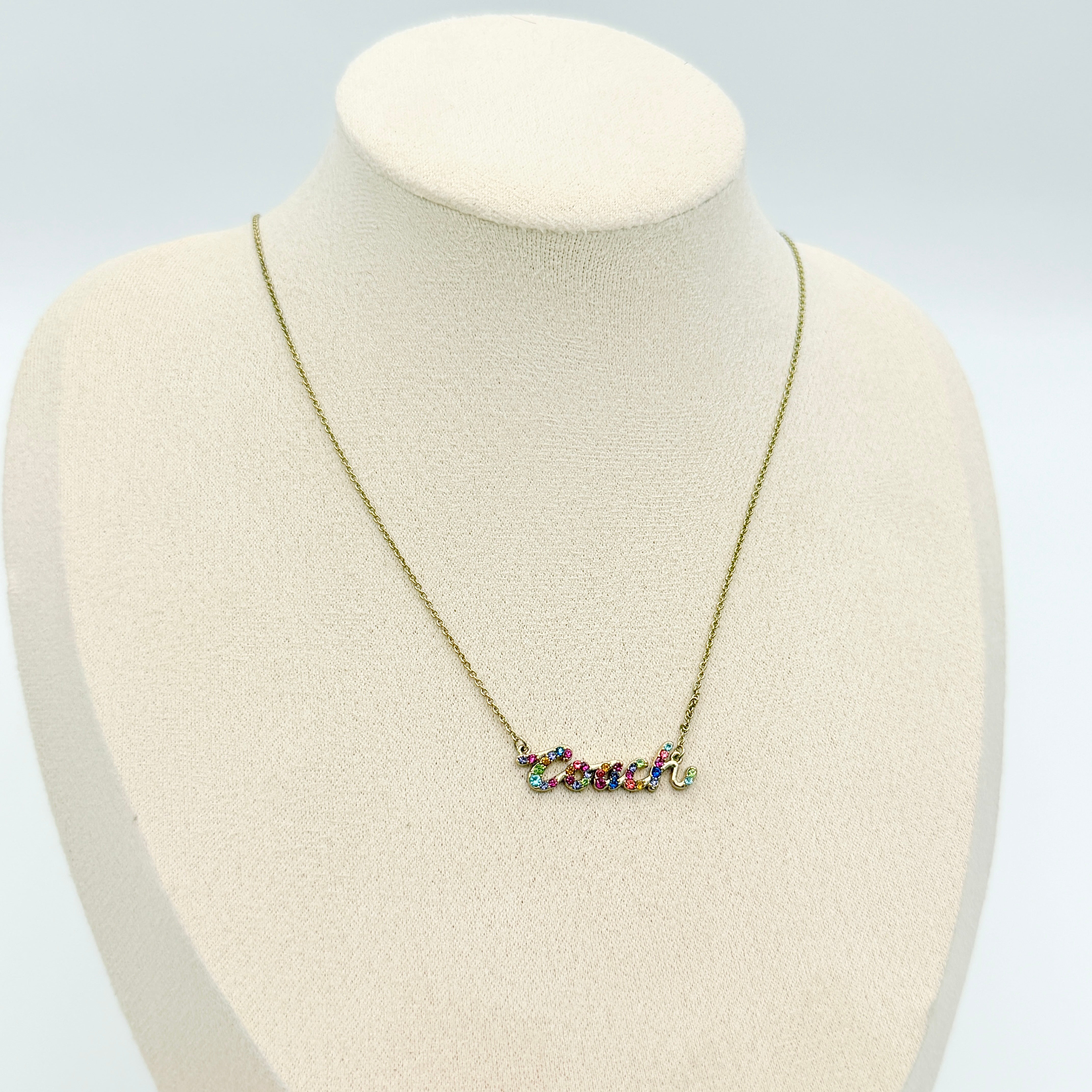Coach Signature Script Rainbow Necklace with multicolour crystals set on a gold-tone chain, displayed in its original Coach box.
