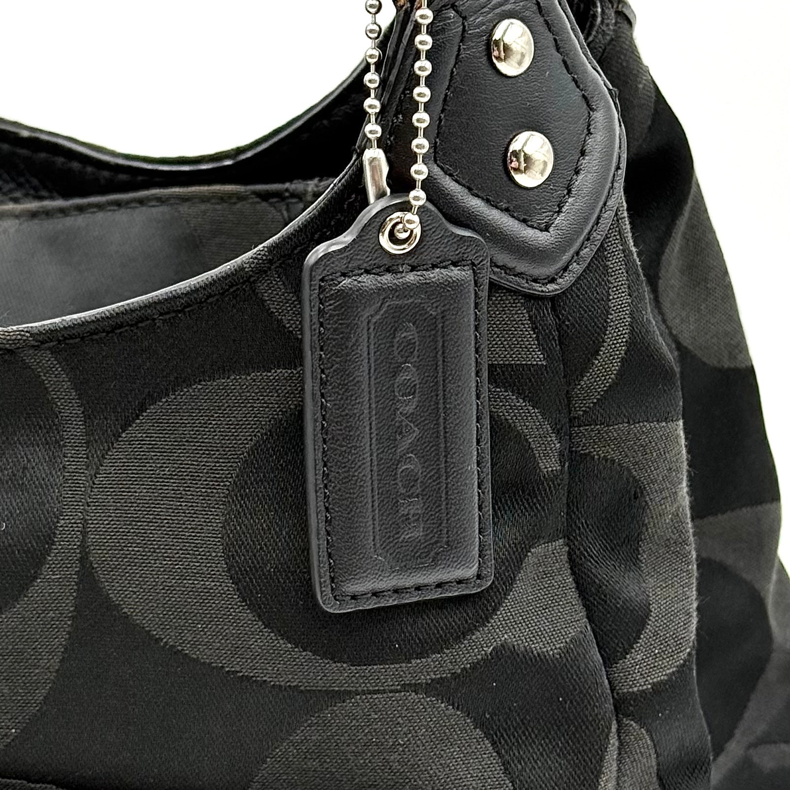 Coach Signature Campbell Hobo Shoulder Bag in black jacquard canvas with leather trim and front buckle pocket, photographed against a white background.