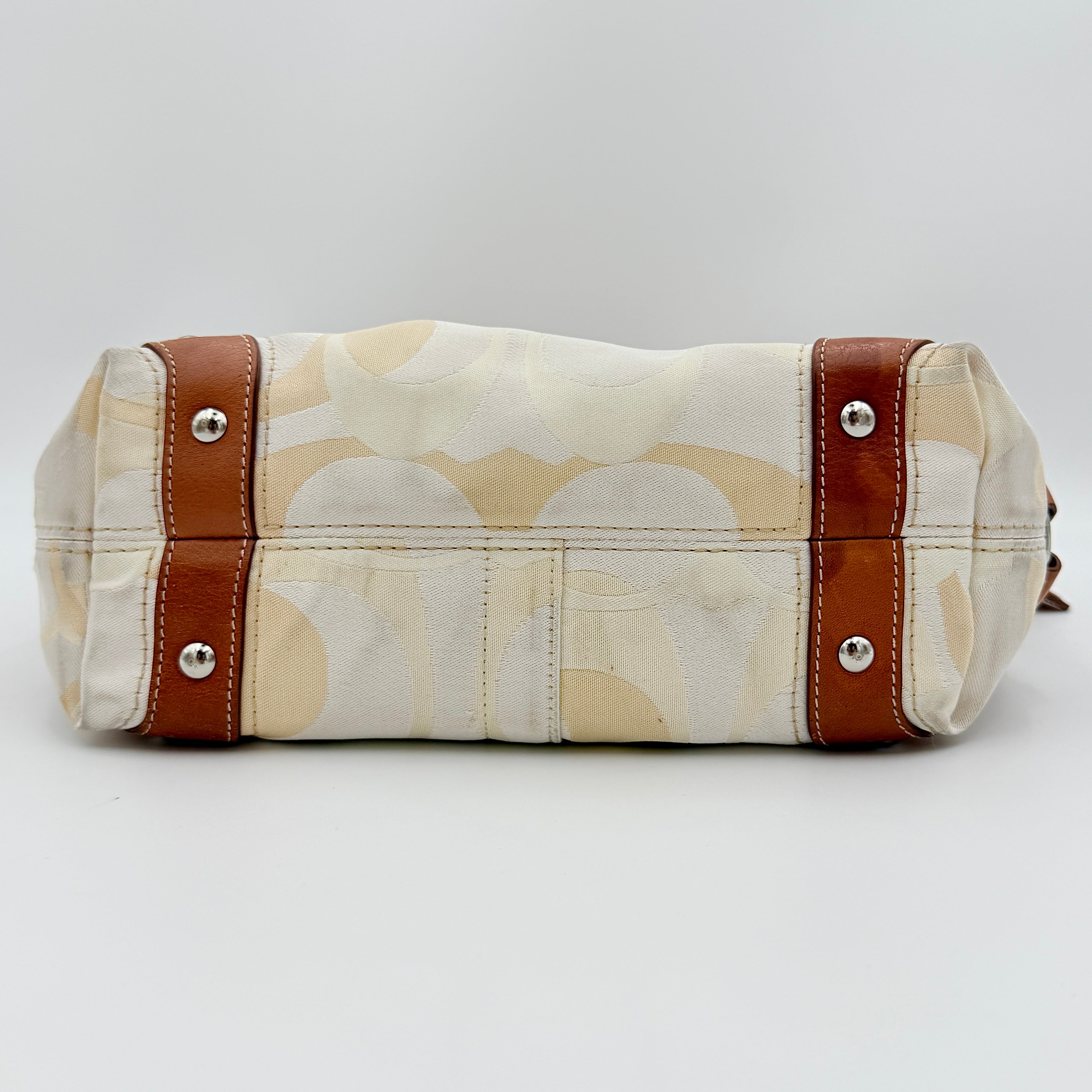 Coach Signature Carly Hobo shoulder bag in cream and brown canvas with tan leather trim and chain-detailed strap.
