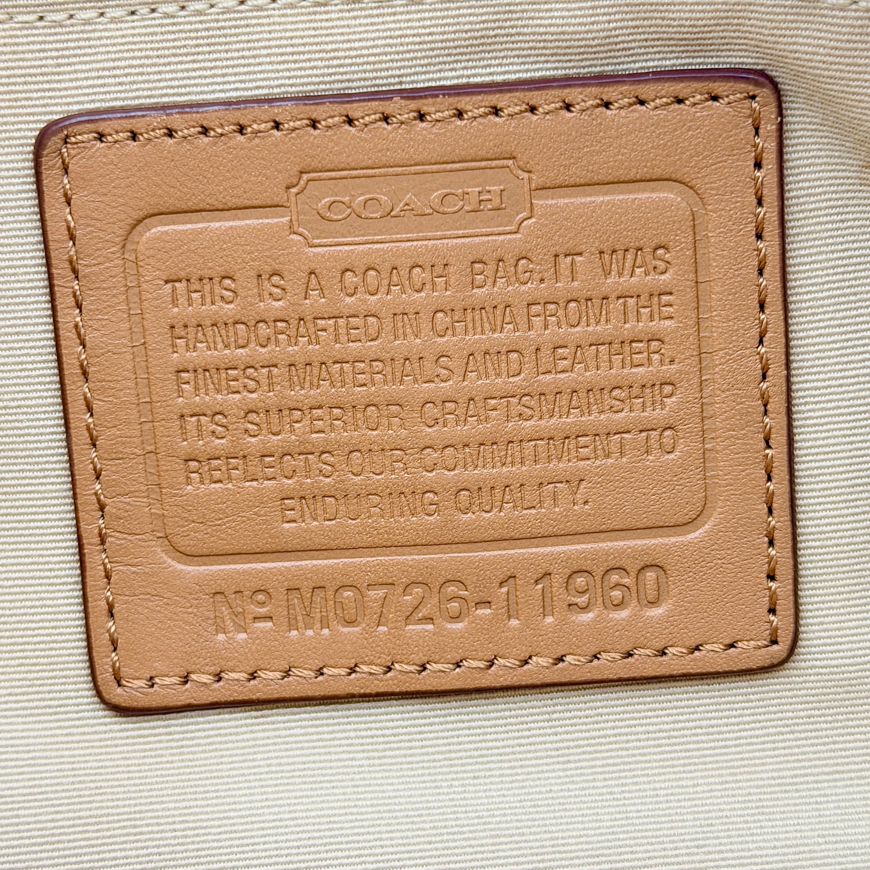 Coach Signature Carly Hobo shoulder bag in cream and brown canvas with tan leather trim and chain-detailed strap.