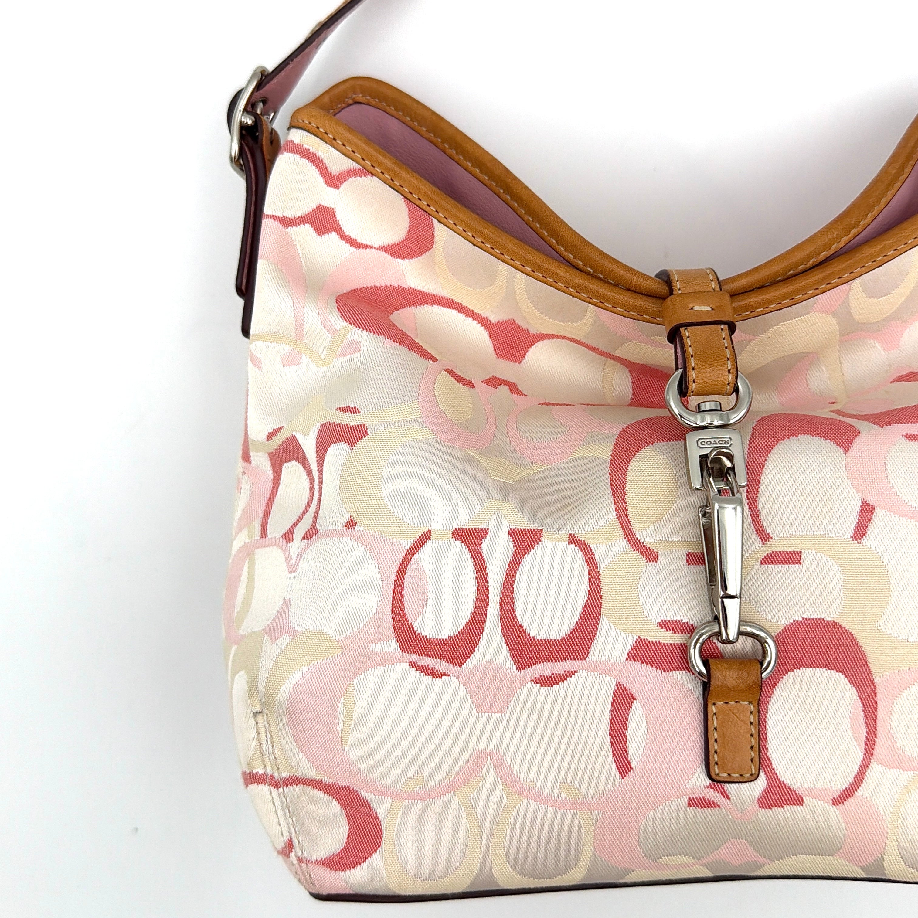 Coach hobo handbag in pink-cream canvas with signature C motif and tan leather trim, featuring a silver clip detail and a structured silhouette.