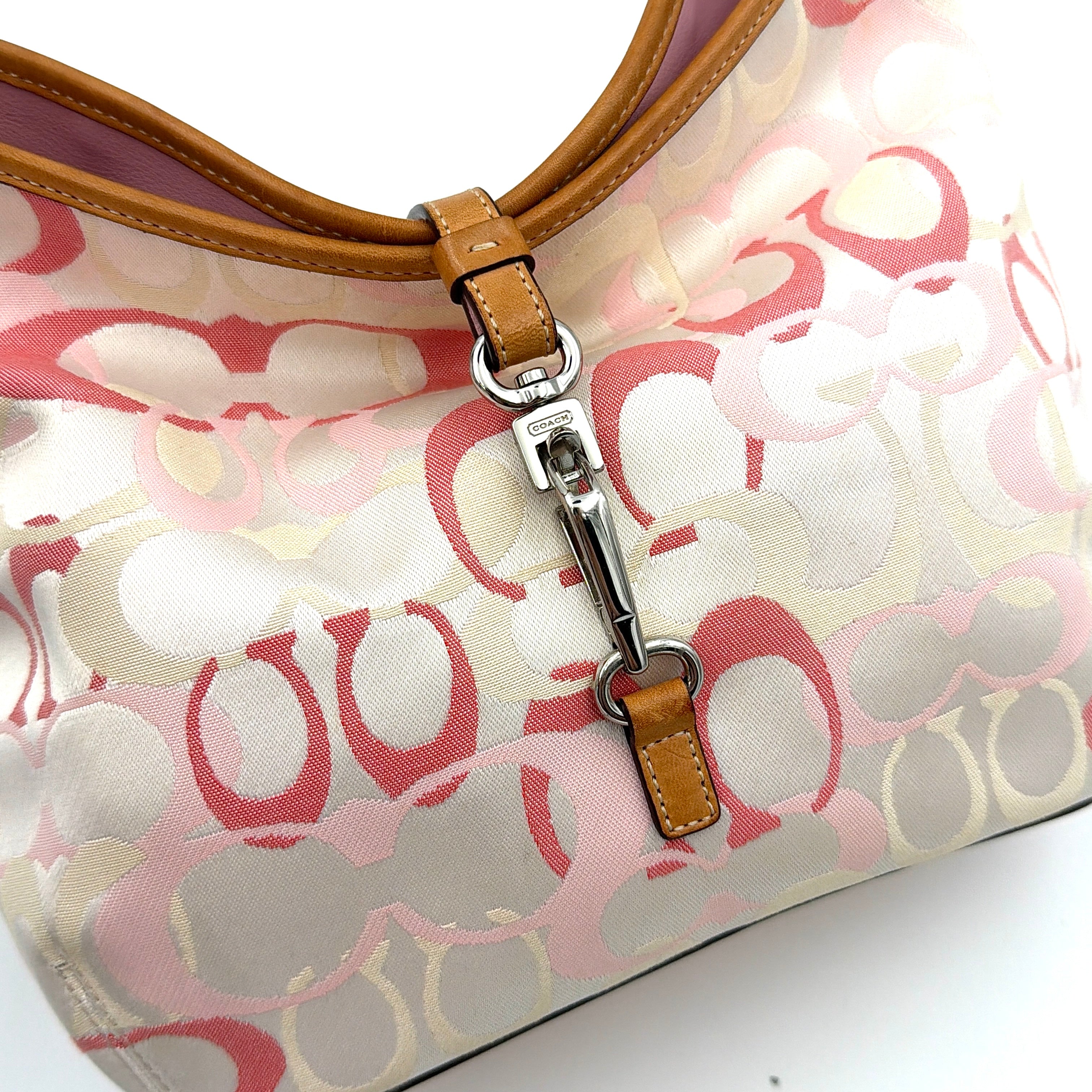 Coach hobo handbag in pink-cream canvas with signature C motif and tan leather trim, featuring a silver clip detail and a structured silhouette.