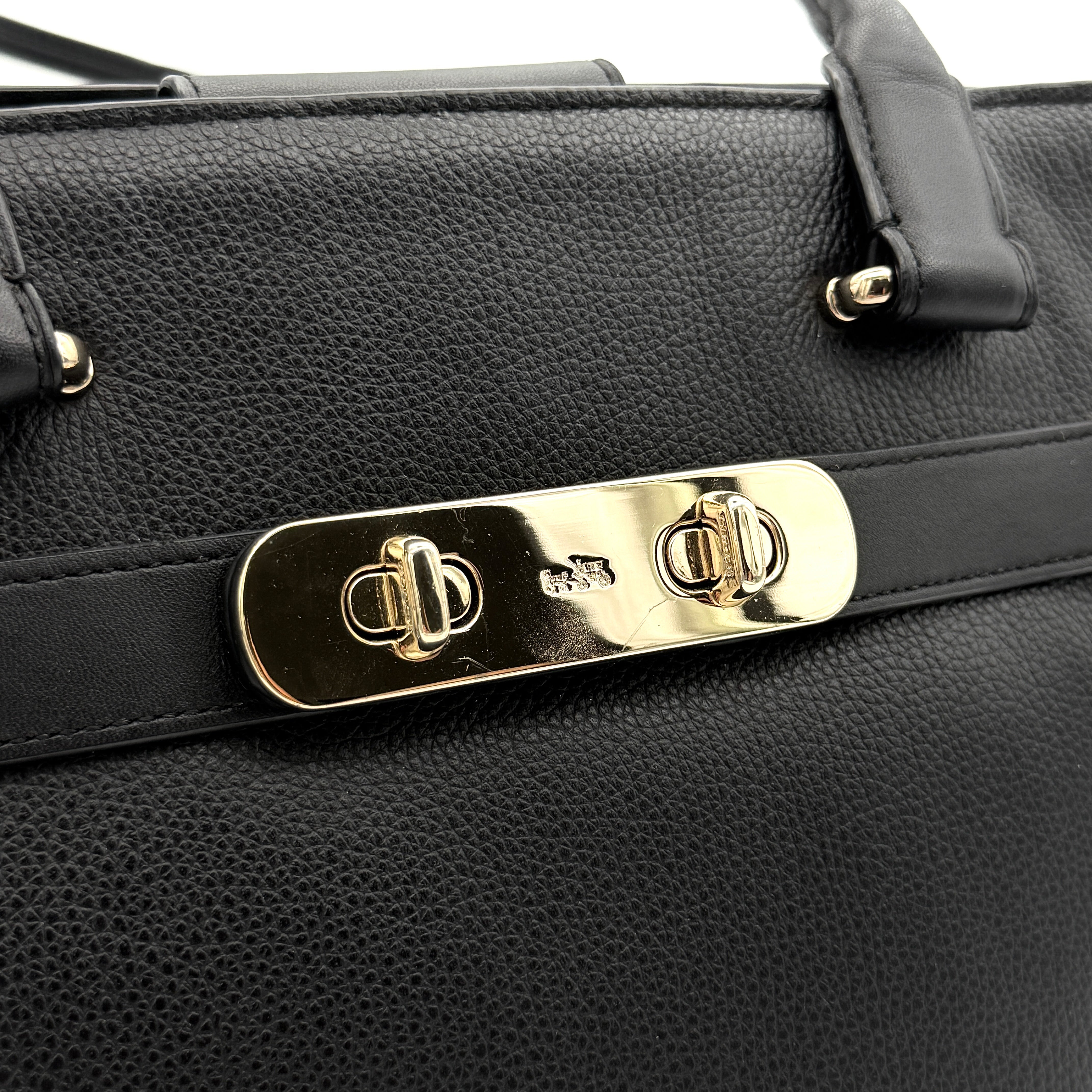 Coach Swagger Carryall in black pebbled leather with gold-tone hardware and double turnlock detail, shown from the front.