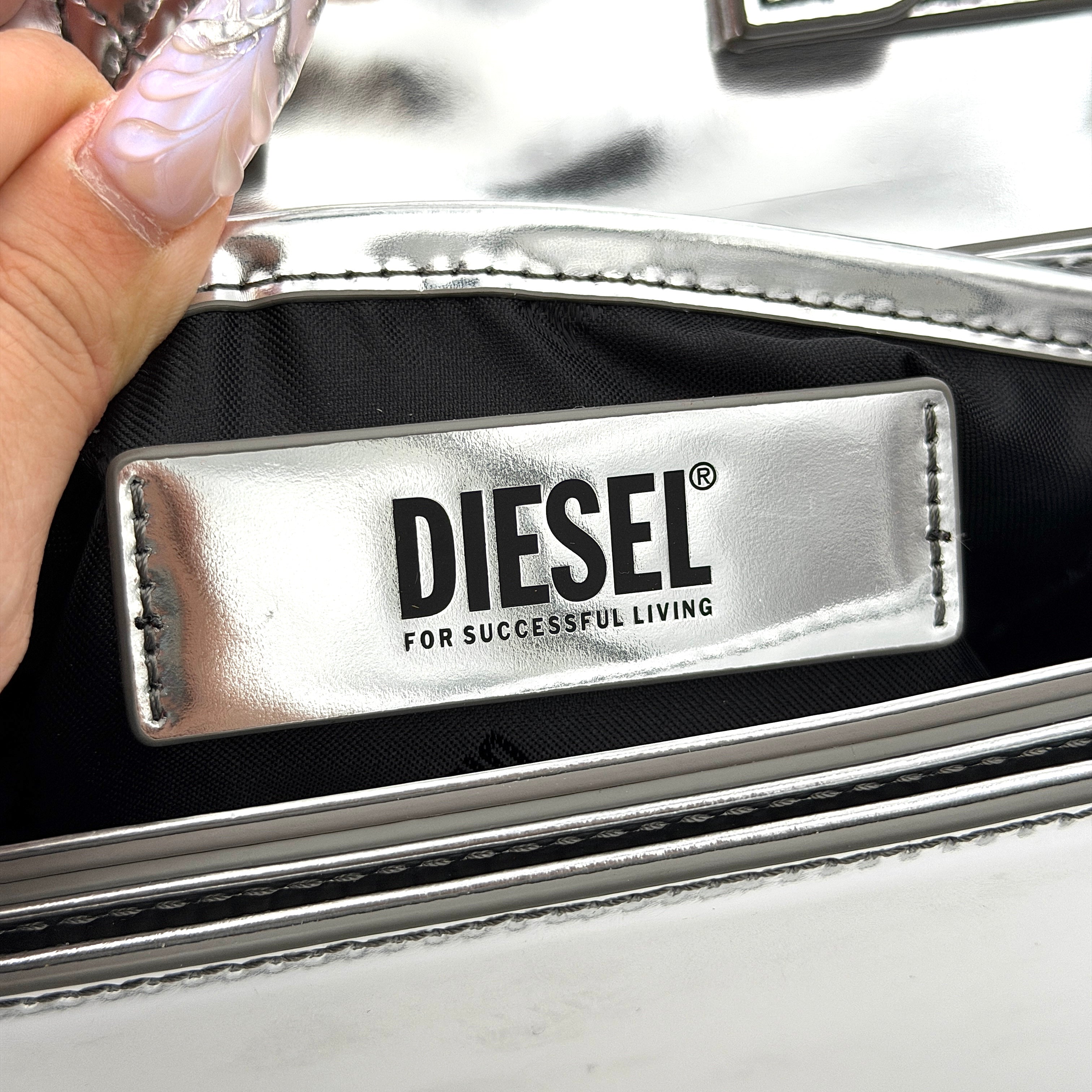 Diesel 1DR 2Way metallic silver shoulder bag with sculptural D logo and detachable strap displayed against a plain background.