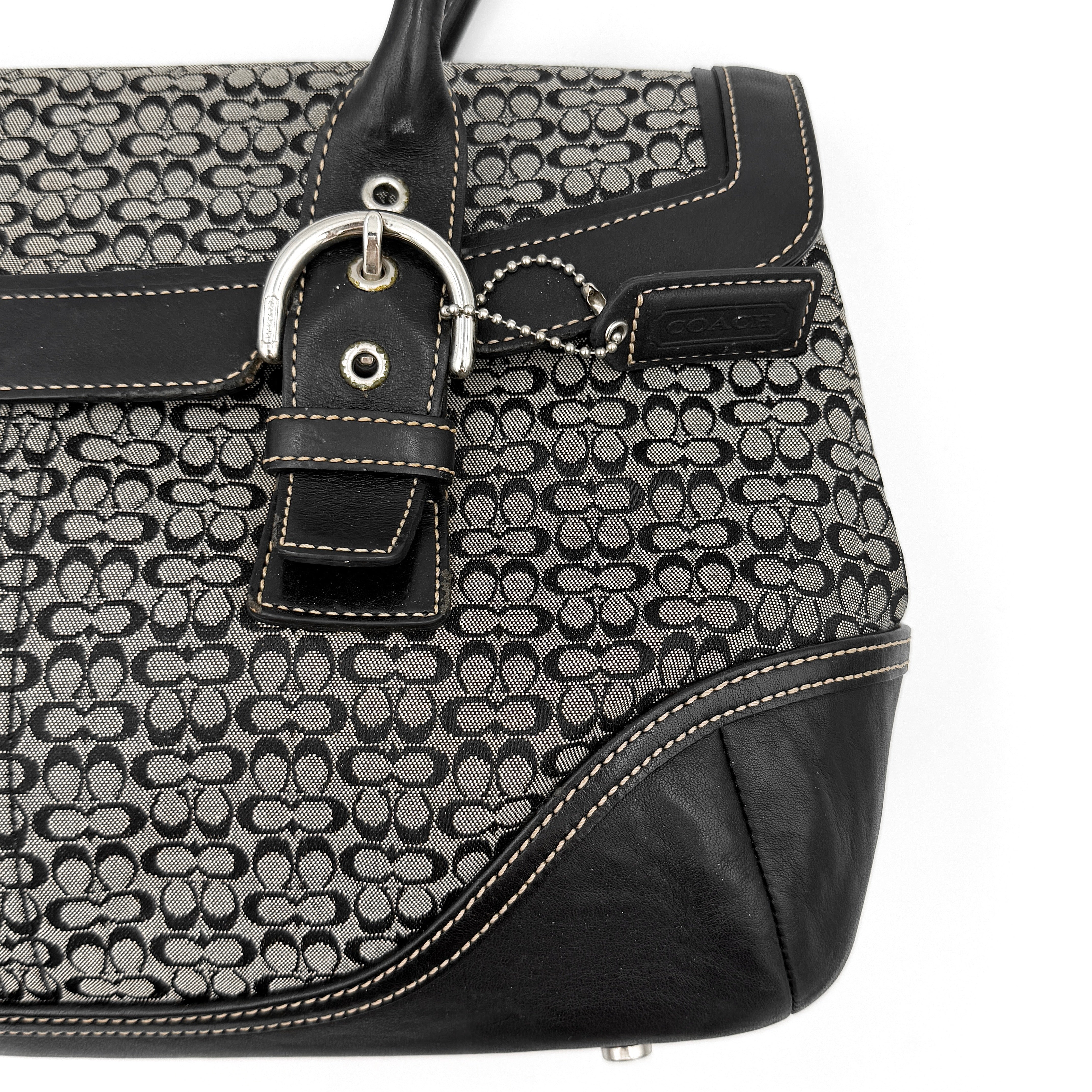 Coach Soho Hampton satchel in grey and black signature jacquard with black leather trim and silver-tone buckle details, presented upright with dual rolled handles.