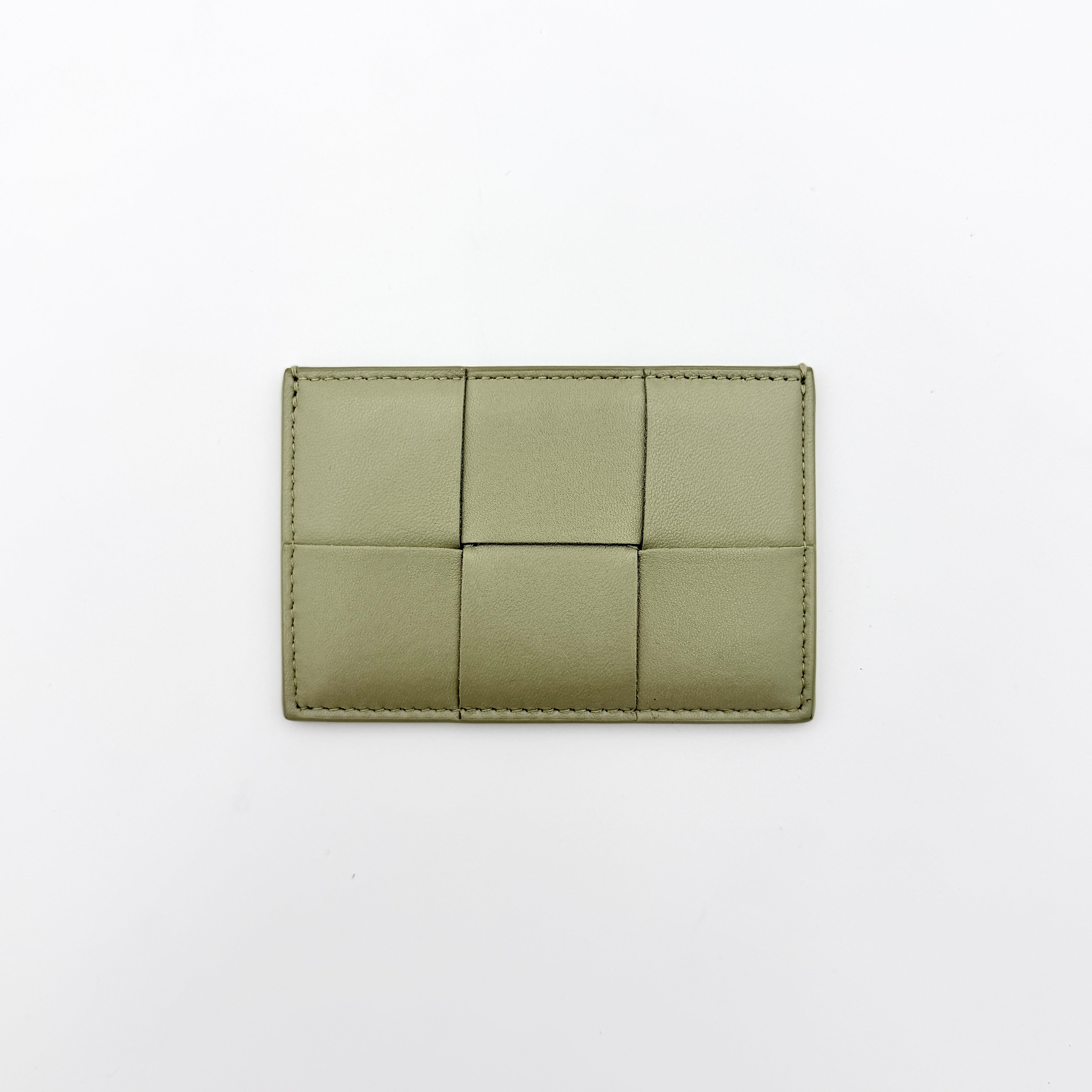 Bottega Veneta Cassette card holder in travertine green leather with signature padded Intrecciato weave, photographed against a white background.
