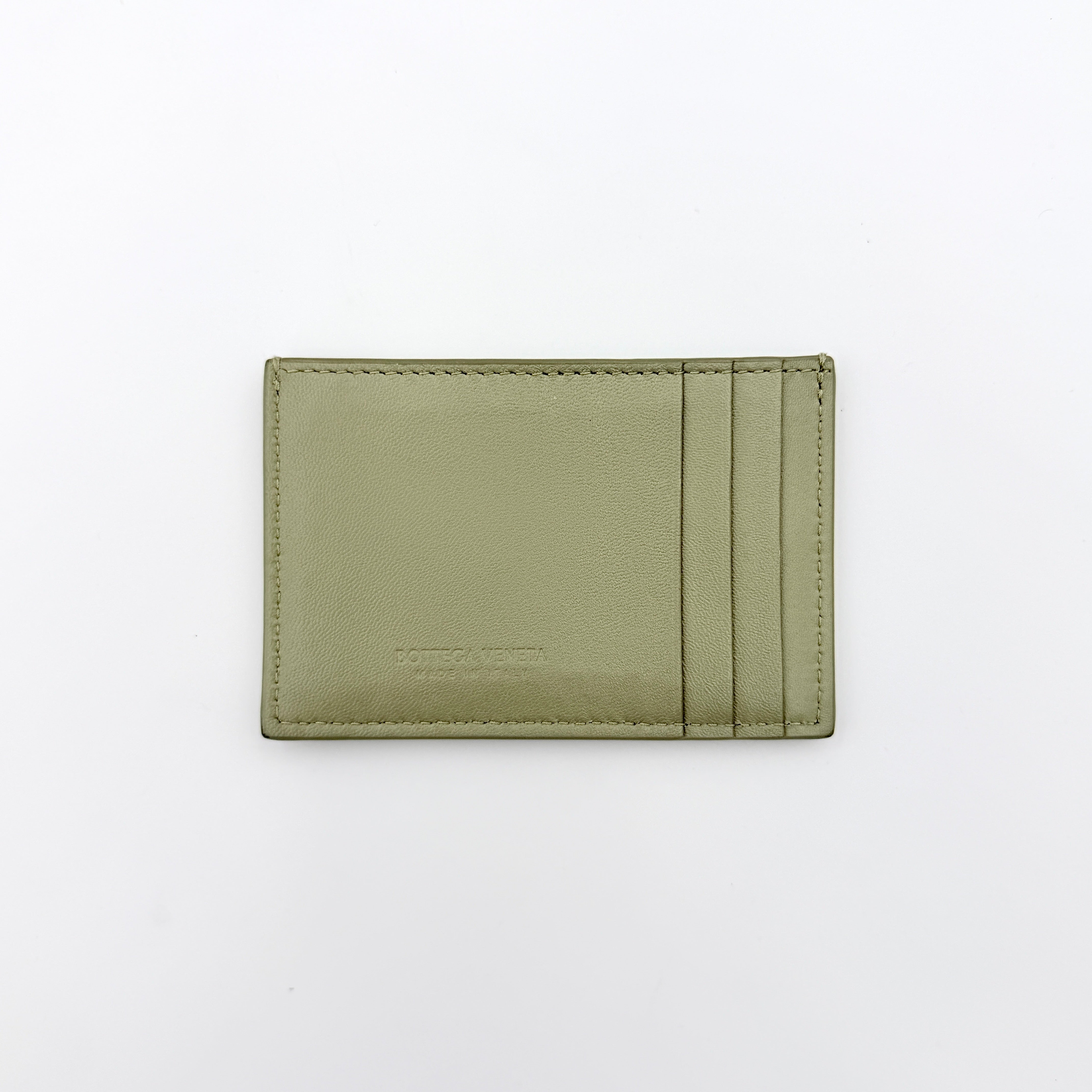 Bottega Veneta Cassette card holder in travertine green leather with signature padded Intrecciato weave, photographed against a white background.