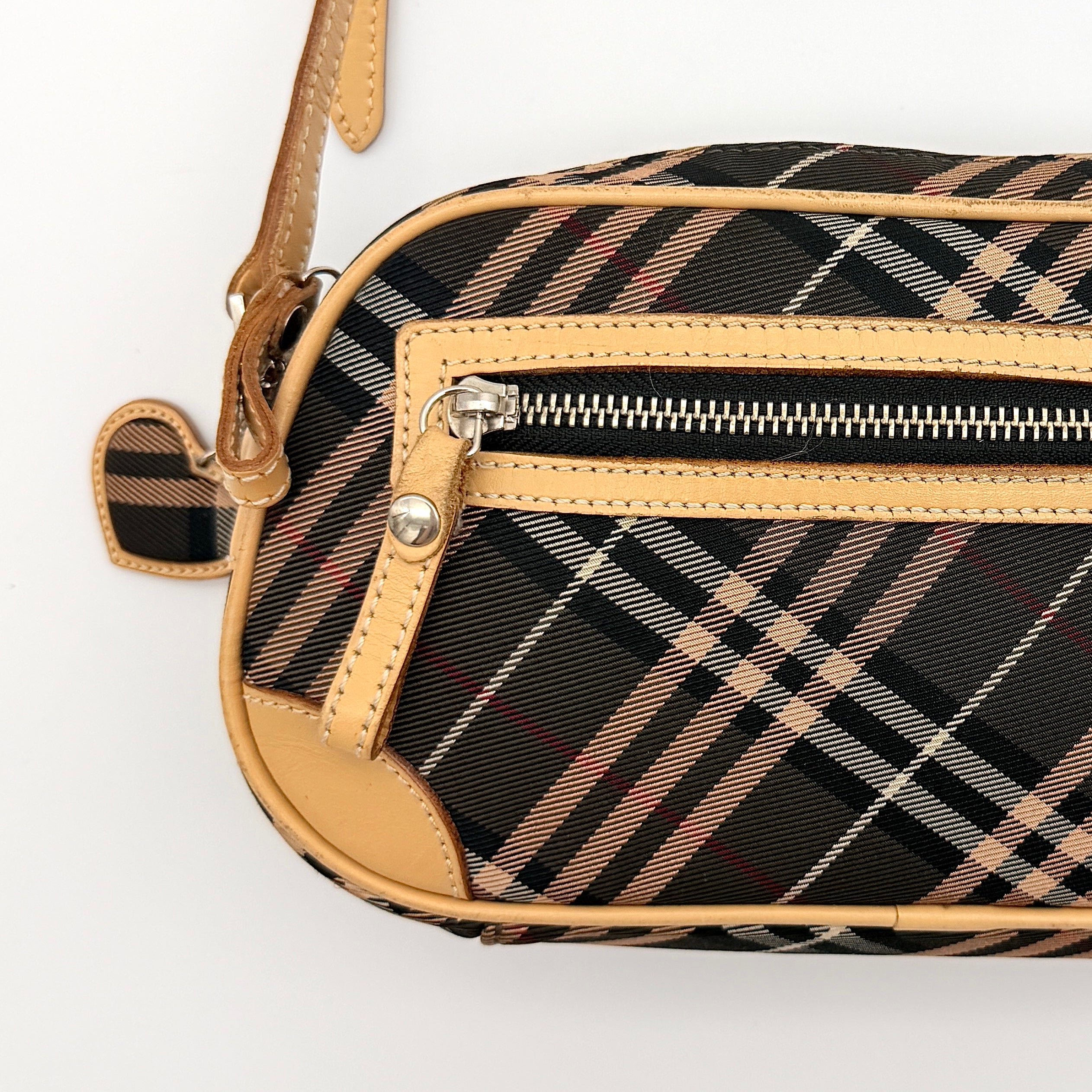 Burberry Blue Label Nova Check crossbody bag with tan leather trim and heart charm, styled on a white background.