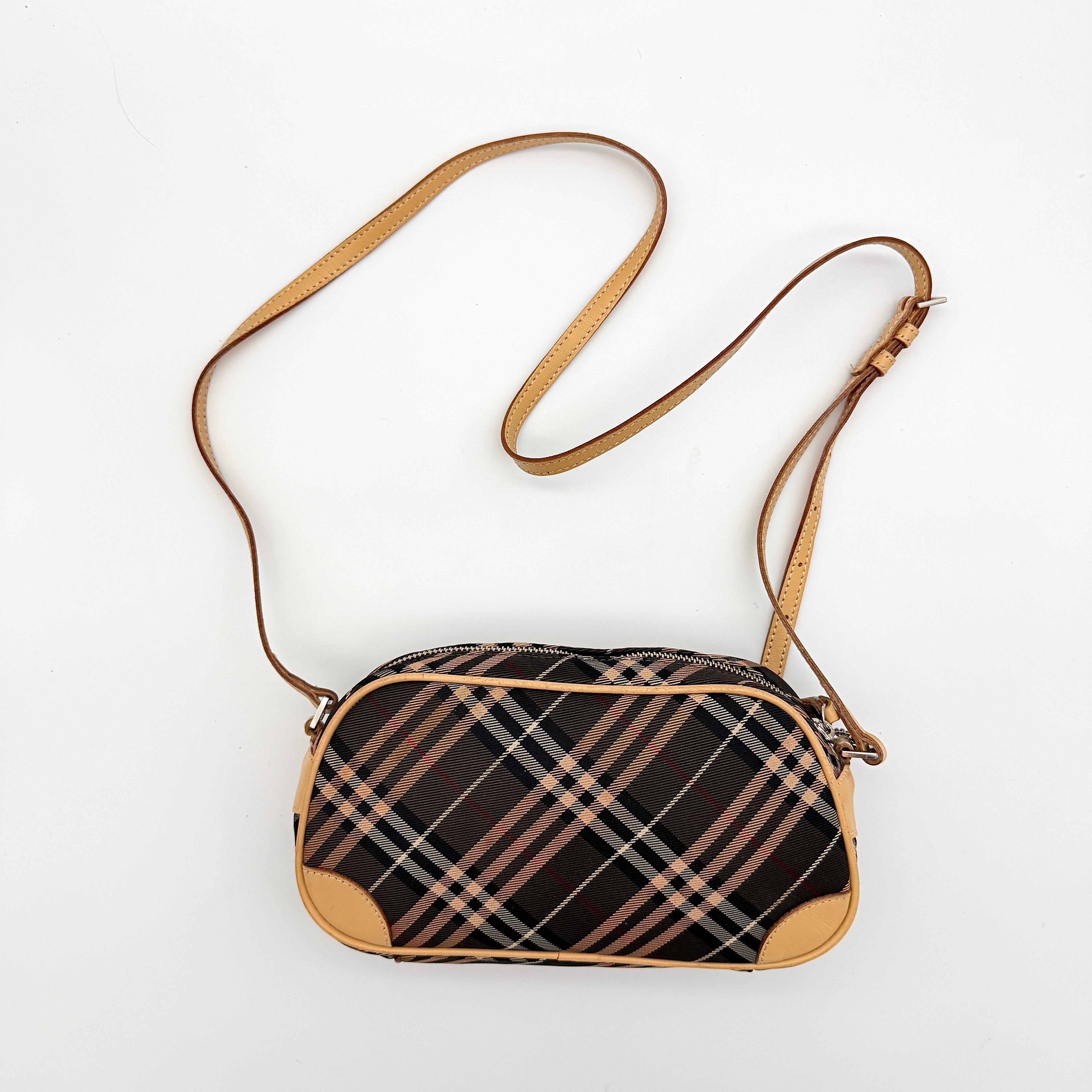 Burberry Blue Label Nova Check crossbody bag with tan leather trim and heart charm, styled on a white background.