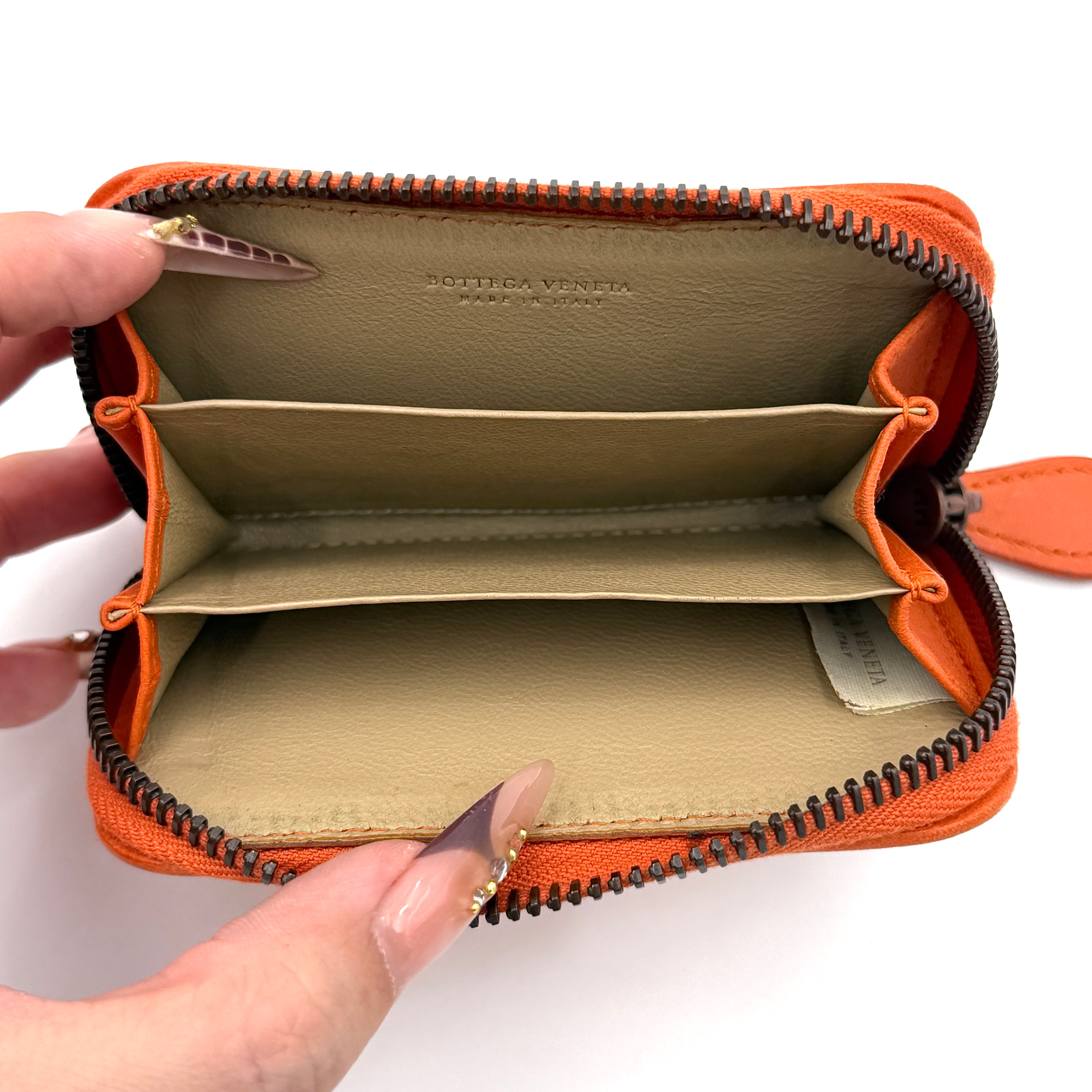 Front view of the Bottega Veneta Intrecciato zip around wallet in orange and white woven leather.