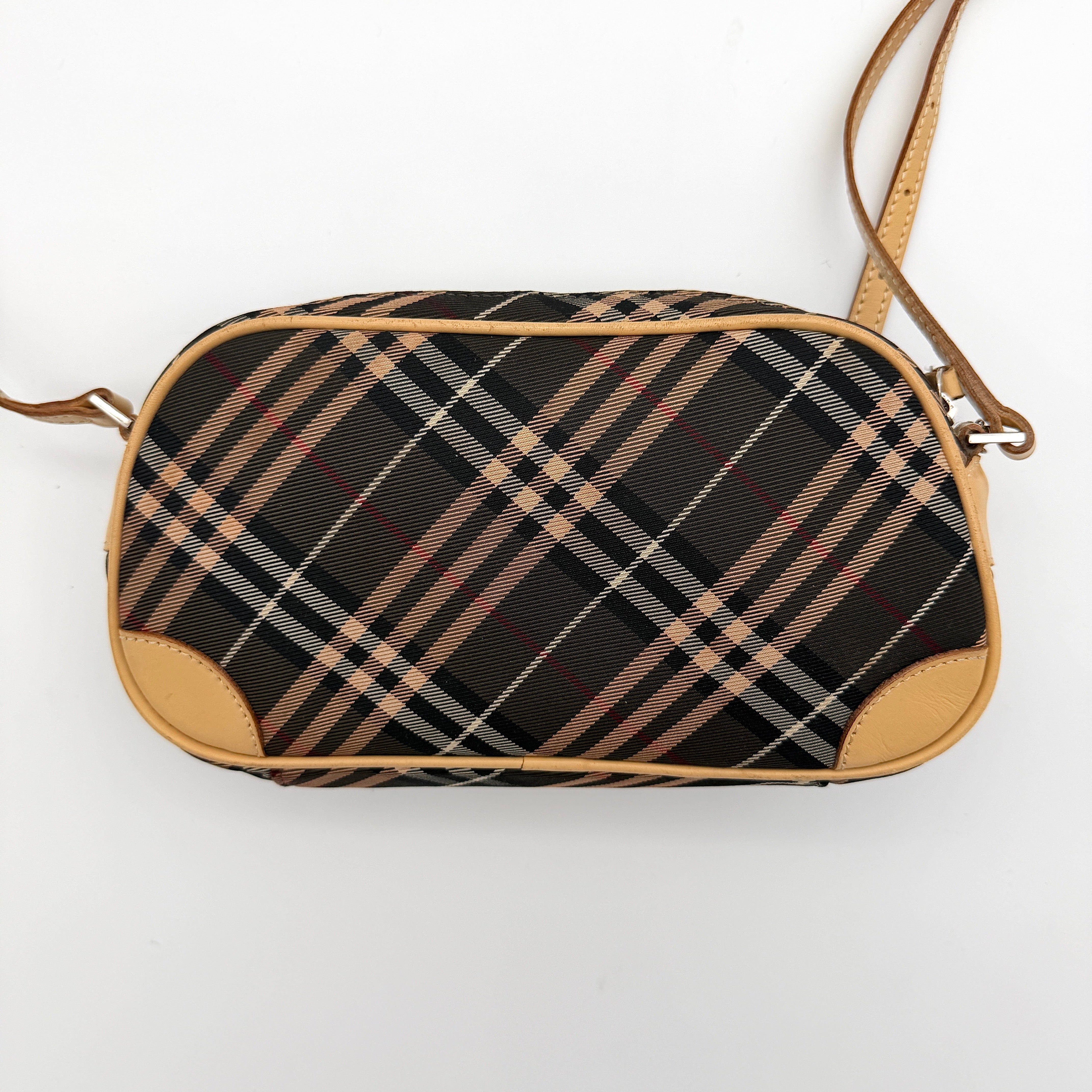 Burberry Blue Label Nova Check crossbody bag with tan leather trim and heart charm, styled on a white background.