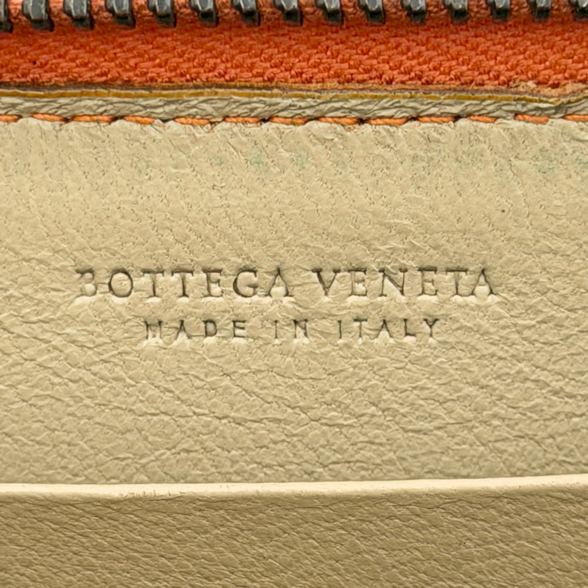 Front view of the Bottega Veneta Intrecciato zip around wallet in orange and white woven leather.