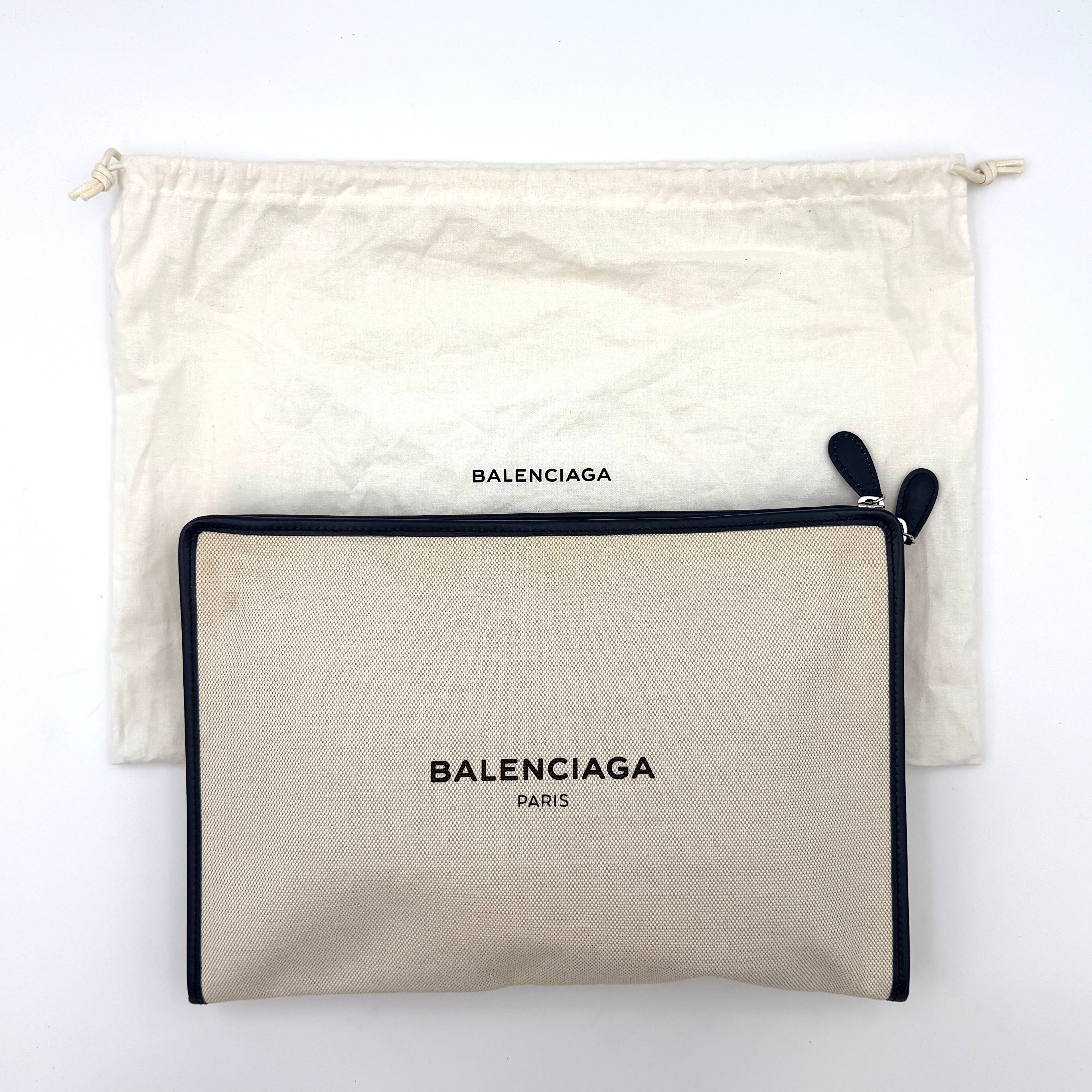Balenciaga large ivory canvas clutch with black leather trim and logo, shown against a plain background.