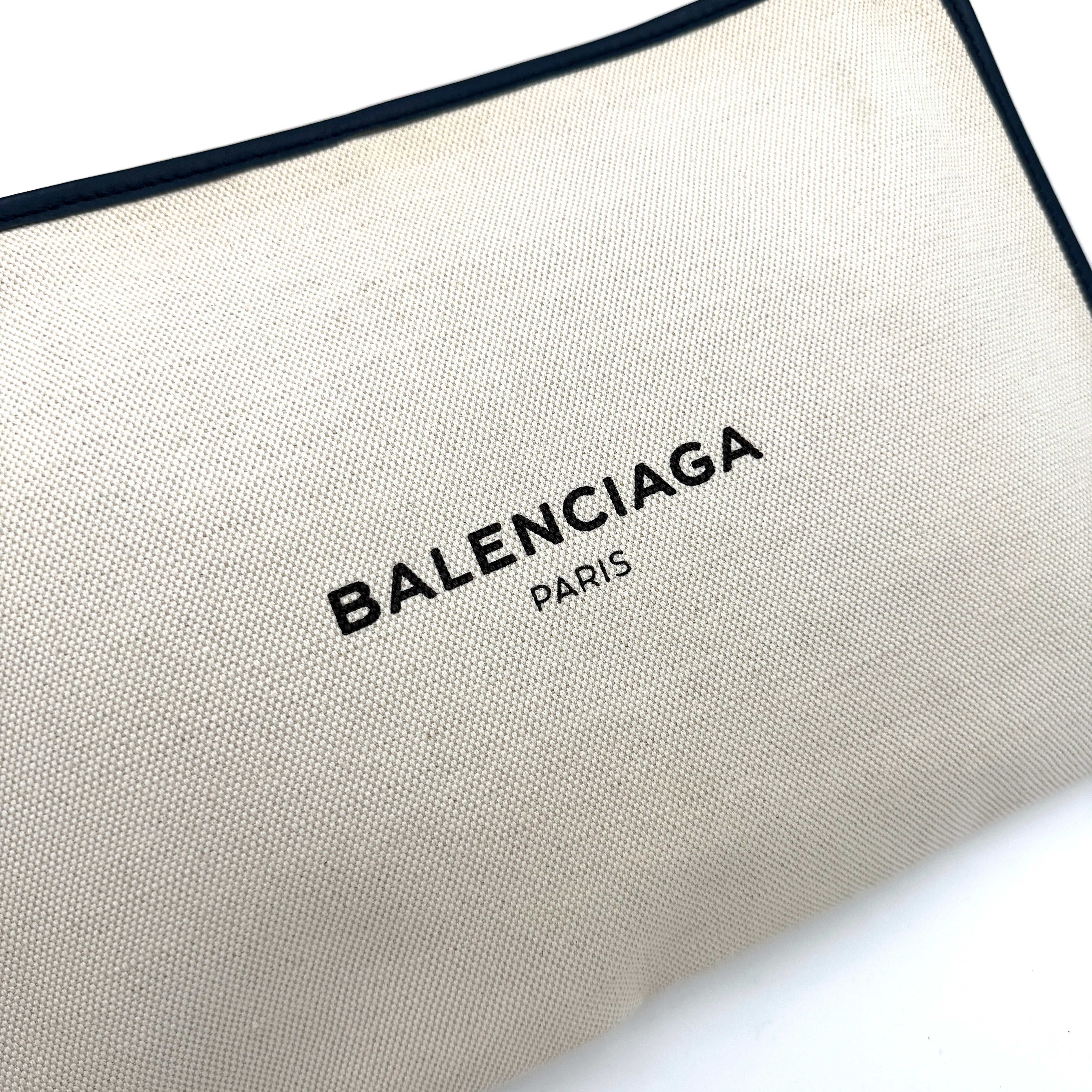 Balenciaga large ivory canvas clutch with black leather trim and logo, shown against a plain background.